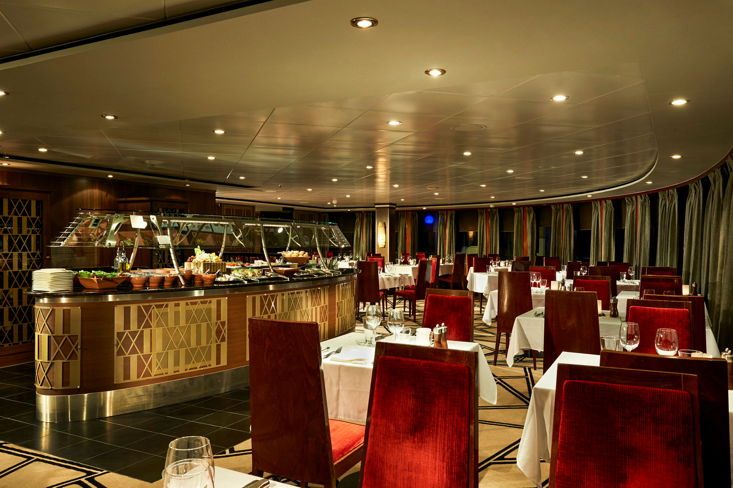 Interiör av en elegant restaurang med rött stoppade stolar och vita dukar. En buffé med mat står centralt. (AI-genererad text)