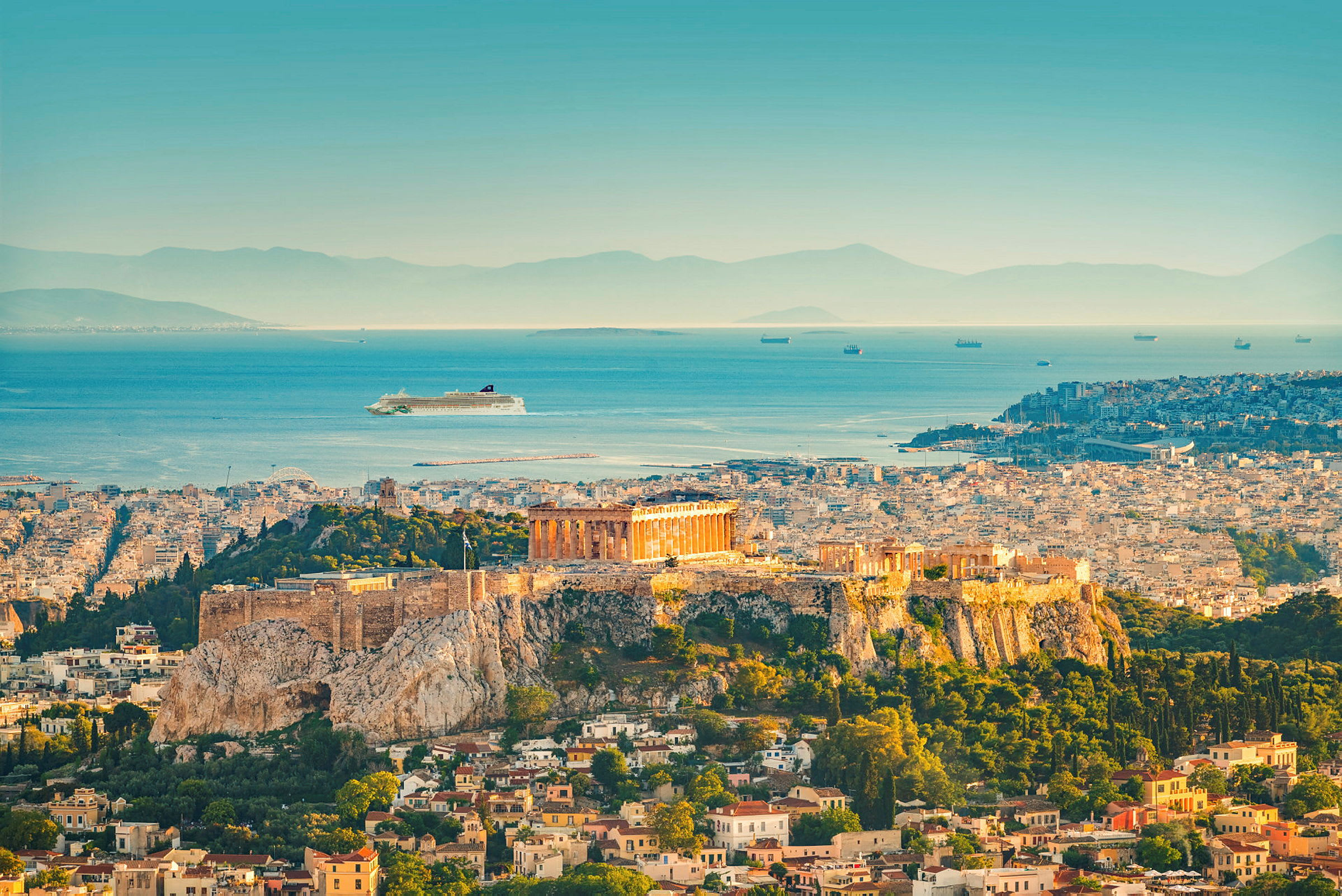 Bild av Akropolis i Aten med Parthenon på en höjd över staden och havet i bakgrunden. (AI-genererad text)