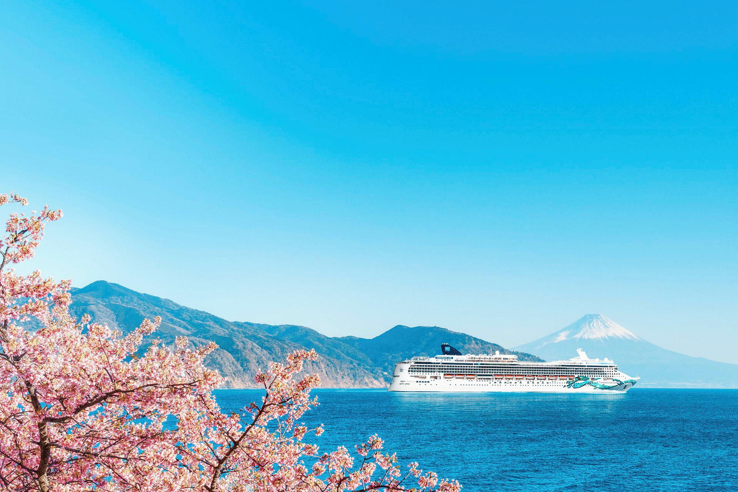 Ett kryssningsfartyg på en blå havsutsikt med berg och Mount Fuji i bakgrunden, samt körsbärsblommor i förgrunden. (AI-genererad text)