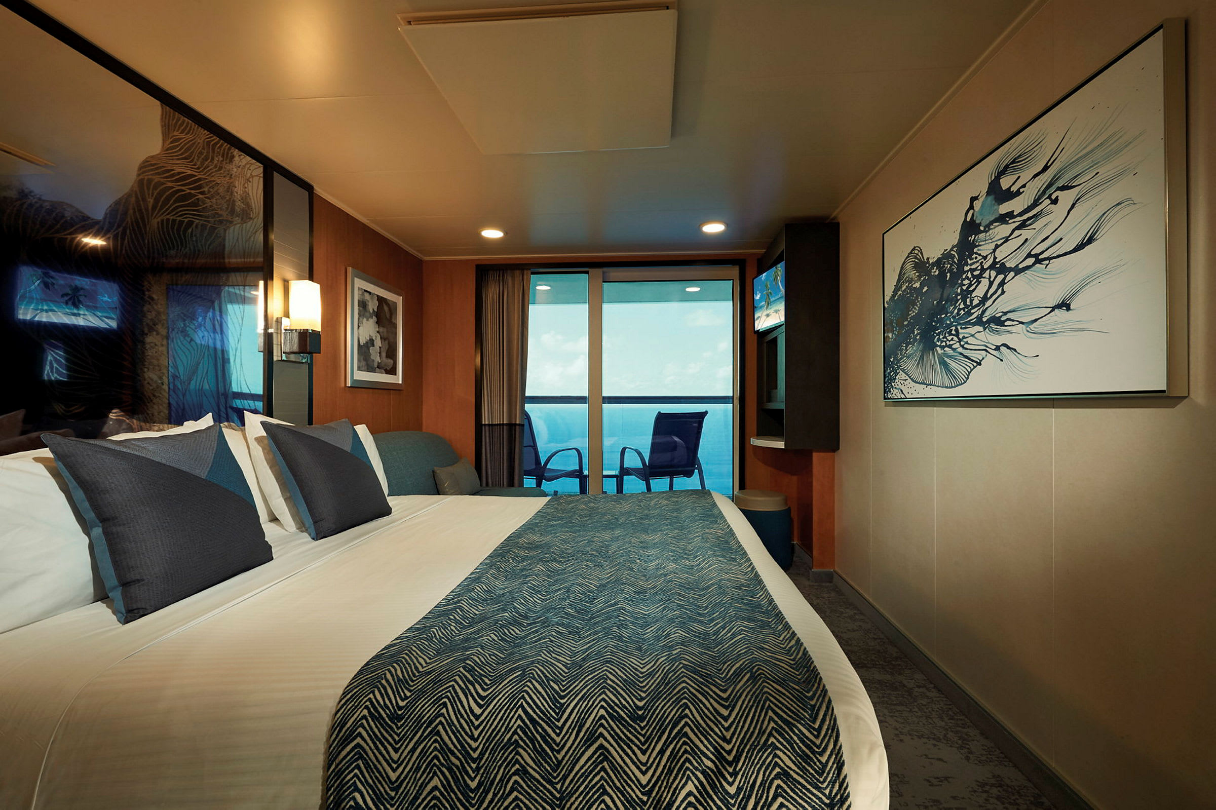 Ett modernt hotellrum med en dubbelsäng, konst på väggarna och en balkong med utsikt över havet. (AI-genererad text)
