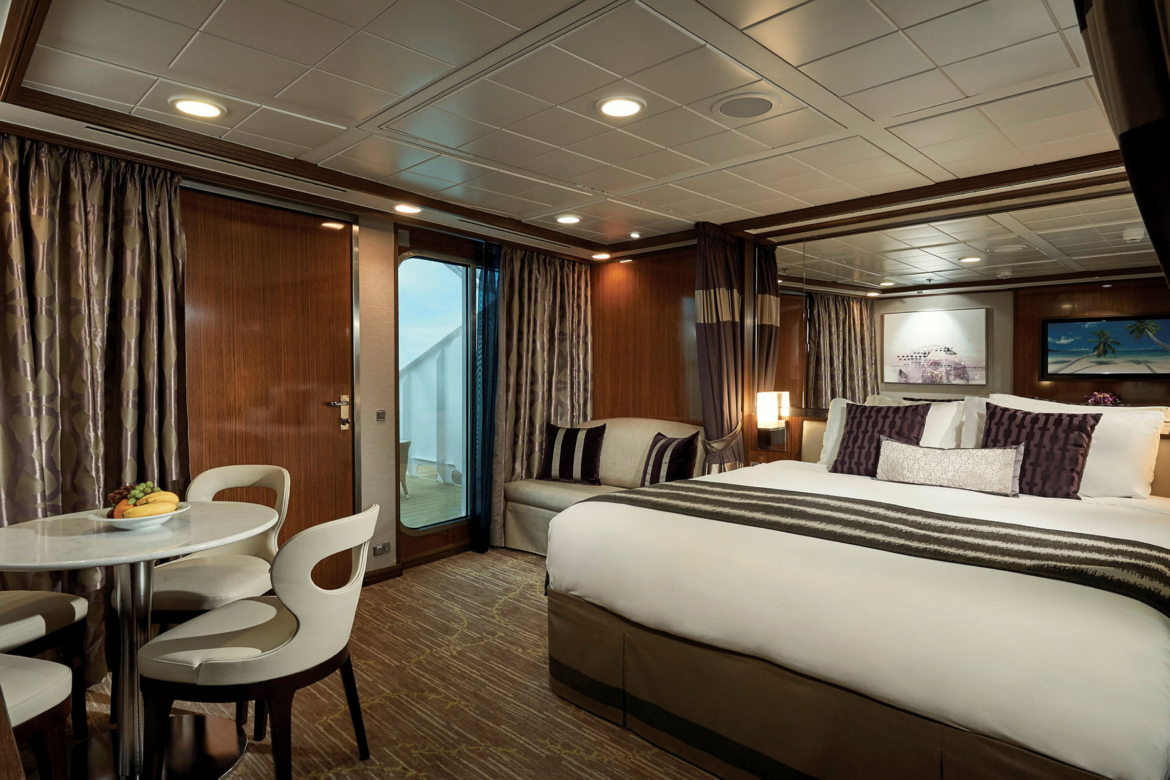 Ett elegant hotellrum med ett stort dubbelsäng, ett litet bord och stolar, samt balkong med utsikt. (AI-genererad text)