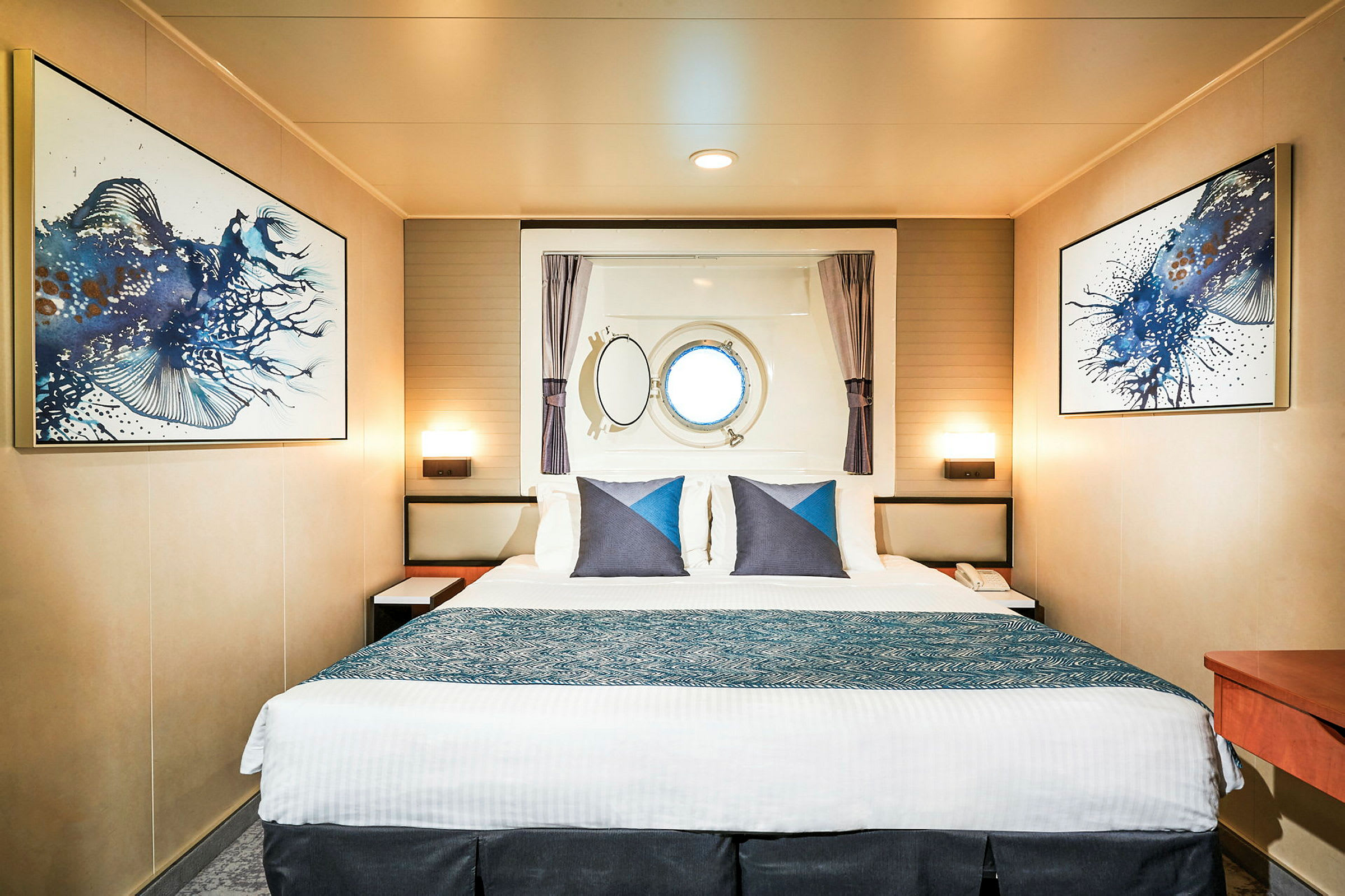 Ett hotellrum med en stor dubbelsäng, väggkonst och ett runt fönster. (AI-genererad text)
