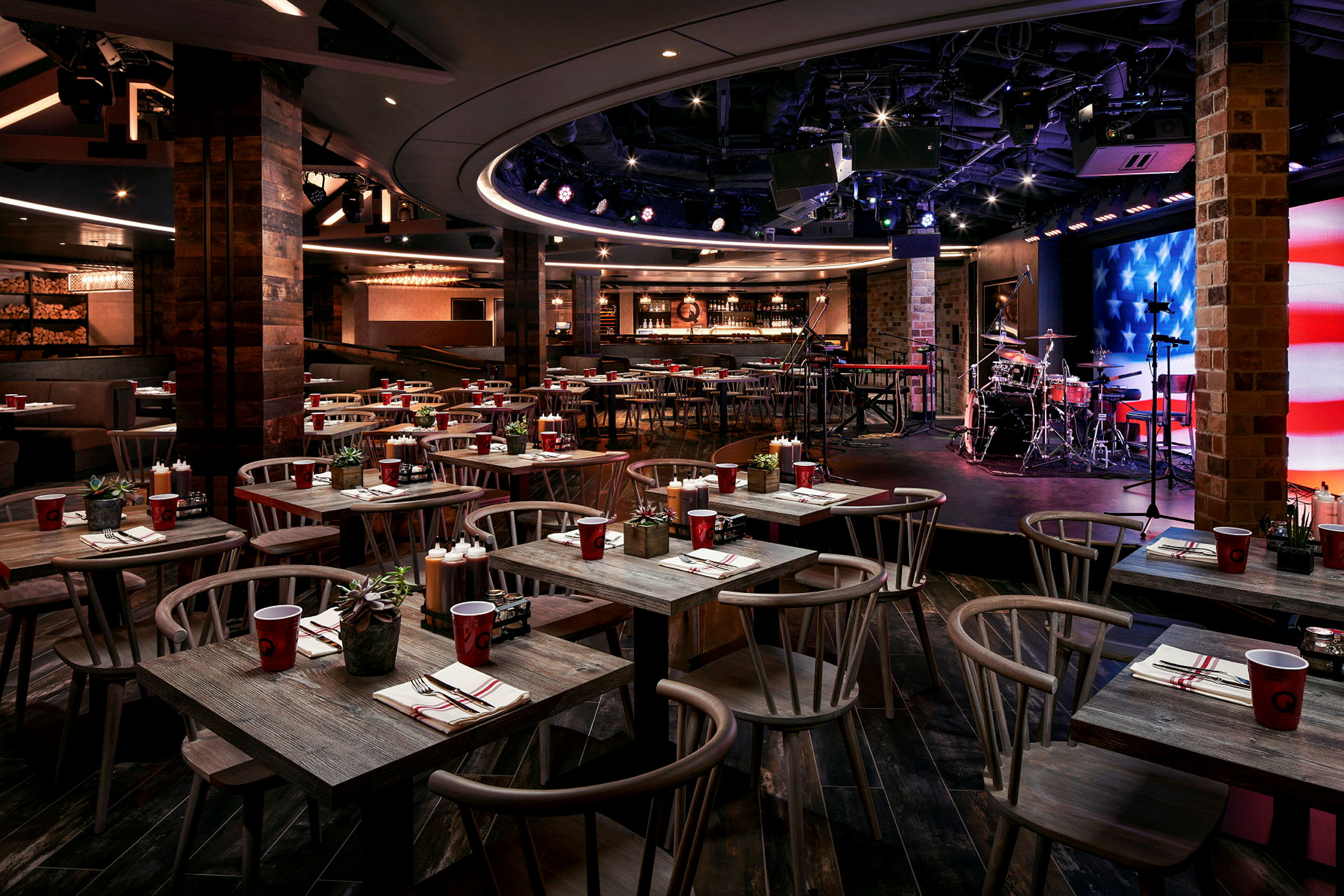 En restaurang med bord och stolar samt en scen med musikutrustning. (AI-genererad text)