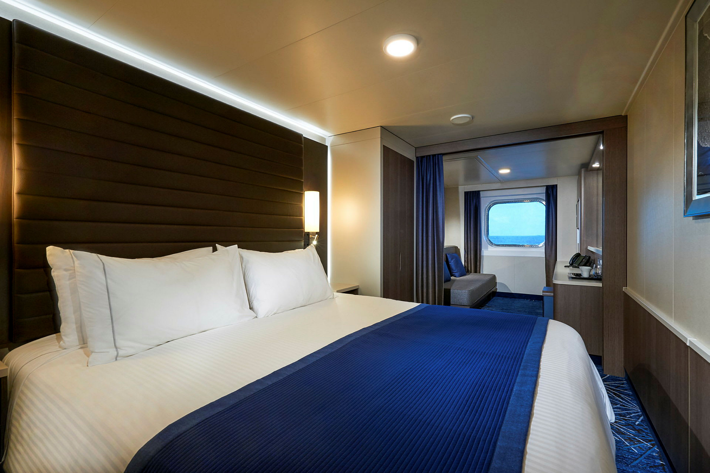 En hotellrum med en stor säng, möbler och ett fönster med utsikt. (AI-genererad text)