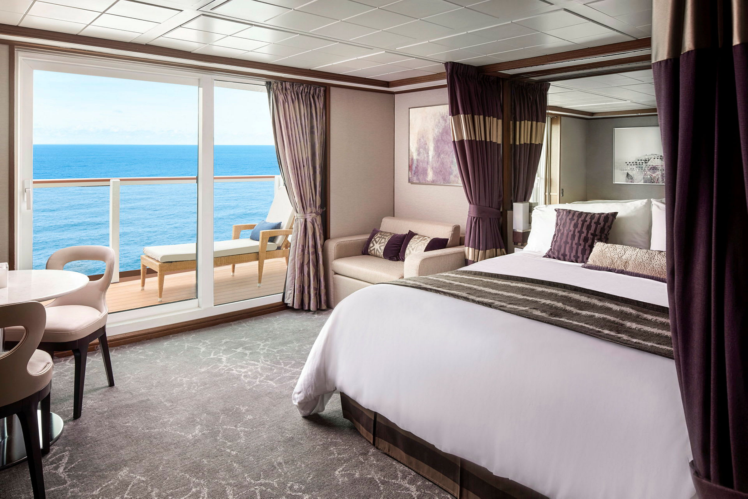 Ett hotellrum med havsutsikt, möblerat med en säng, soffa och ett runt bord. (AI-genererad text)