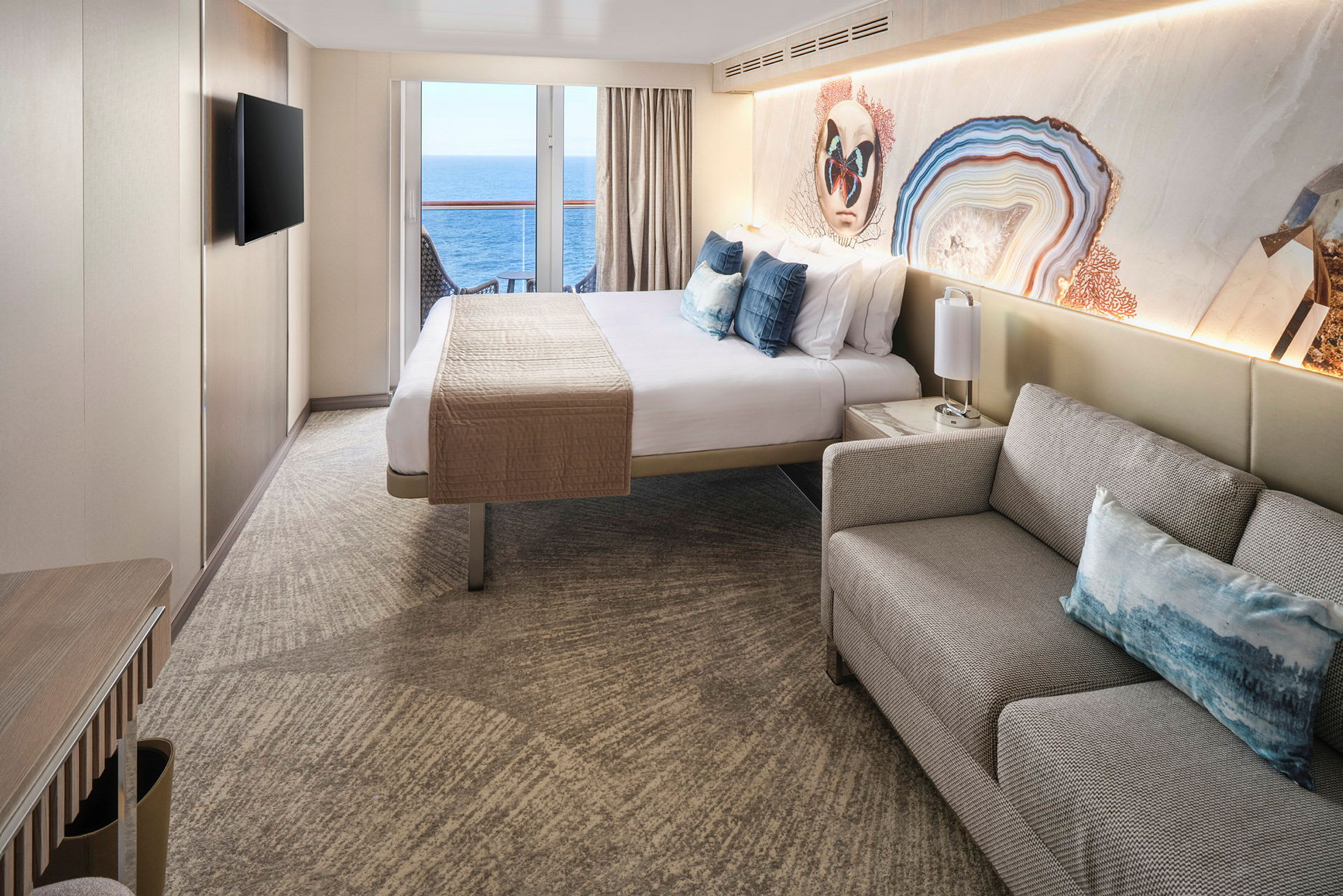 Interiörbild av ett hotellrum med en dubbelsäng, soffa och en balkong med utsikt över havet. (AI-genererad text)