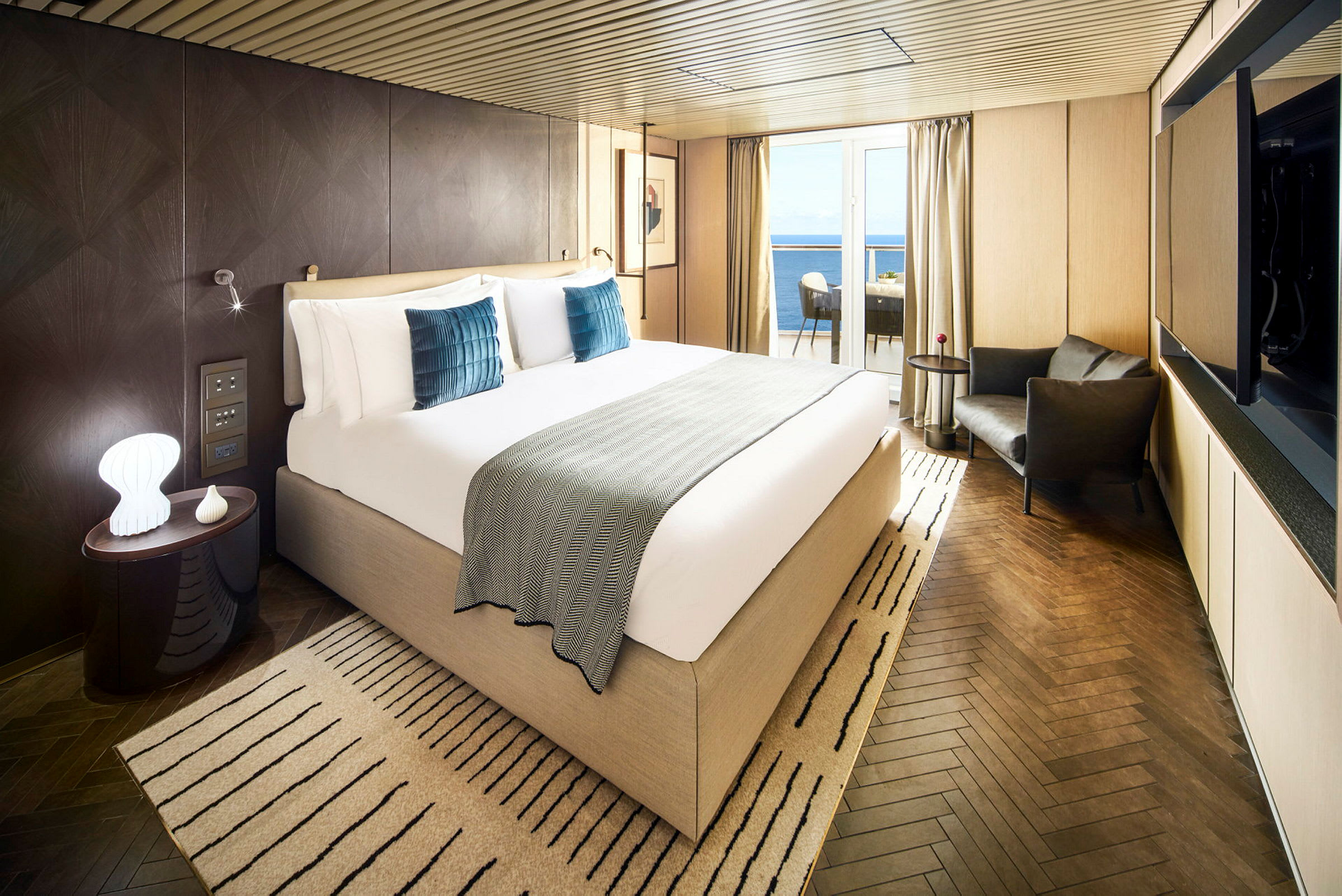 Hotellrum med stor säng, sittgrupp och balkong med utsikt över havet. (AI-genererad text)