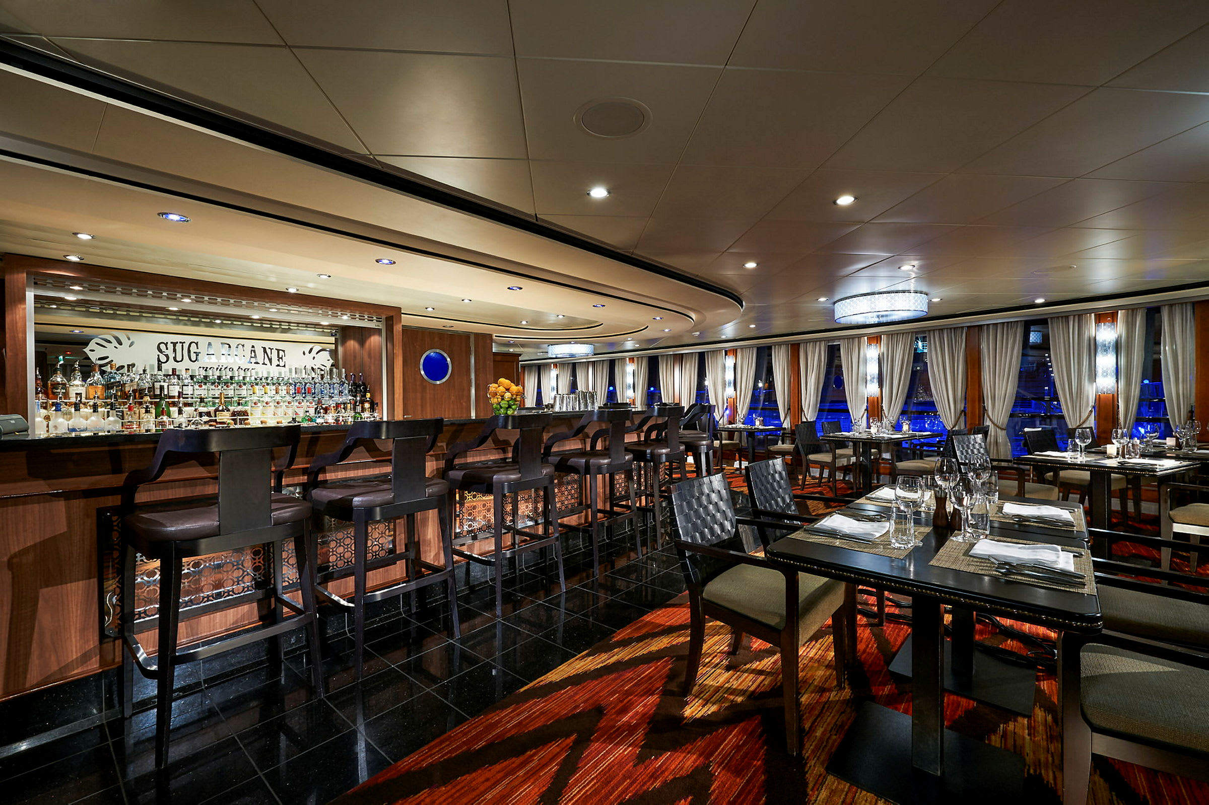 En välbelyst restaurang med en bardisk och stolar i förgrunden. (AI-genererad text)
