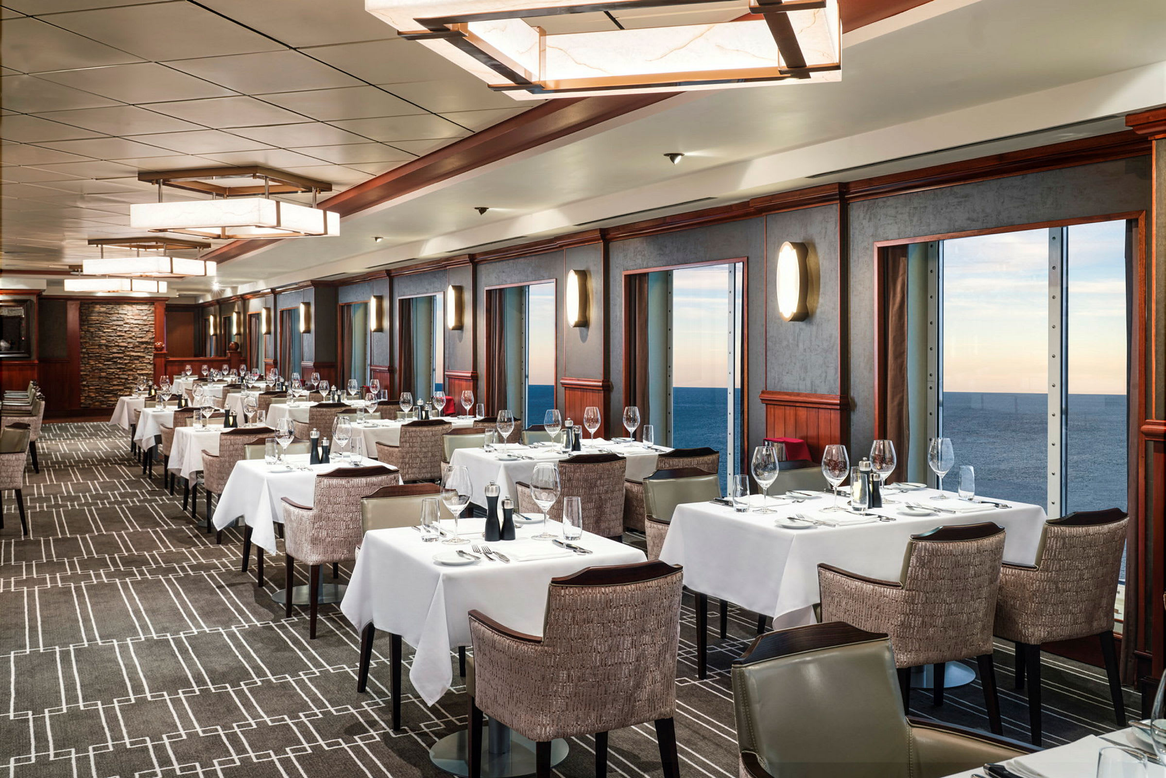 En elegant matsal med dukade bord och utsikt över havet genom stora fönster. (AI-genererad text)