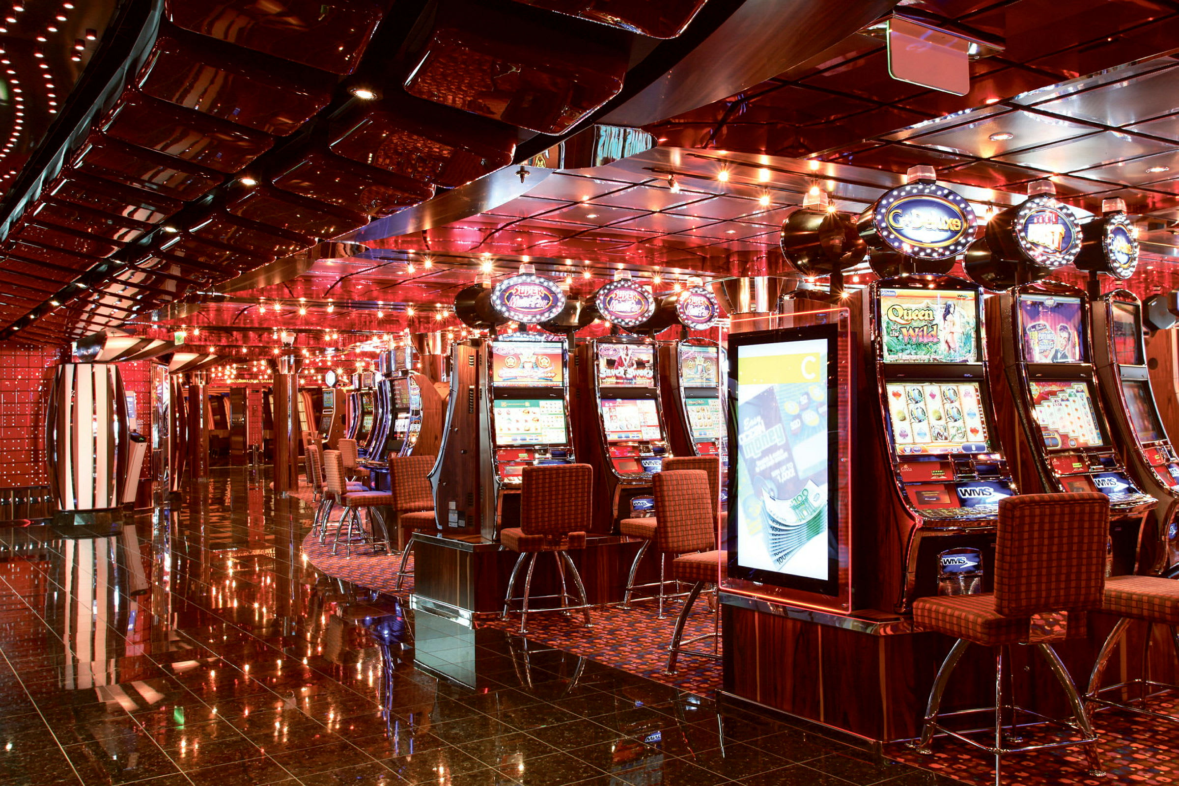 Ett rum med flera spelautomater, stolar och lågt upplyst tak. (AI-genererad text)