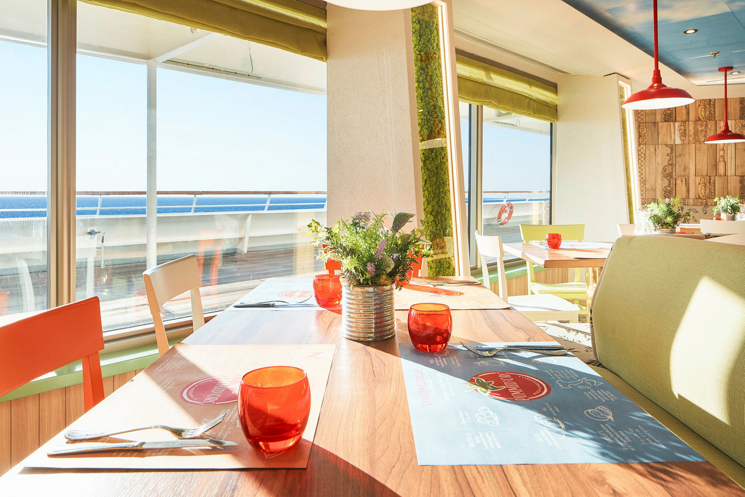 Solig restaurang med bord, stolar och utsikt mot havet. (AI-genererad text)