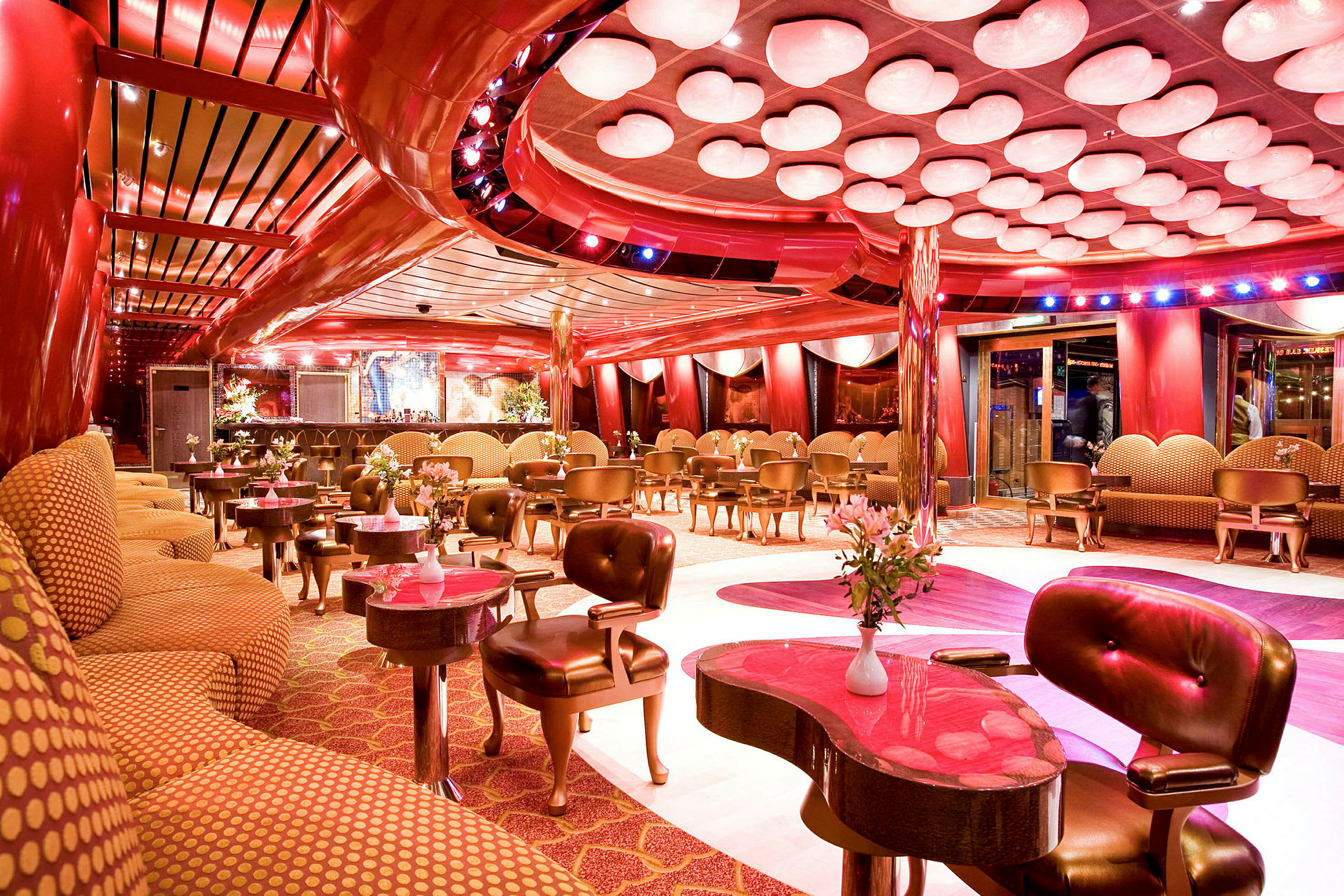 En elegant lounge med röda och gulddetaljer, modern inredning och blomsterdekorationer. (AI-genererad text)