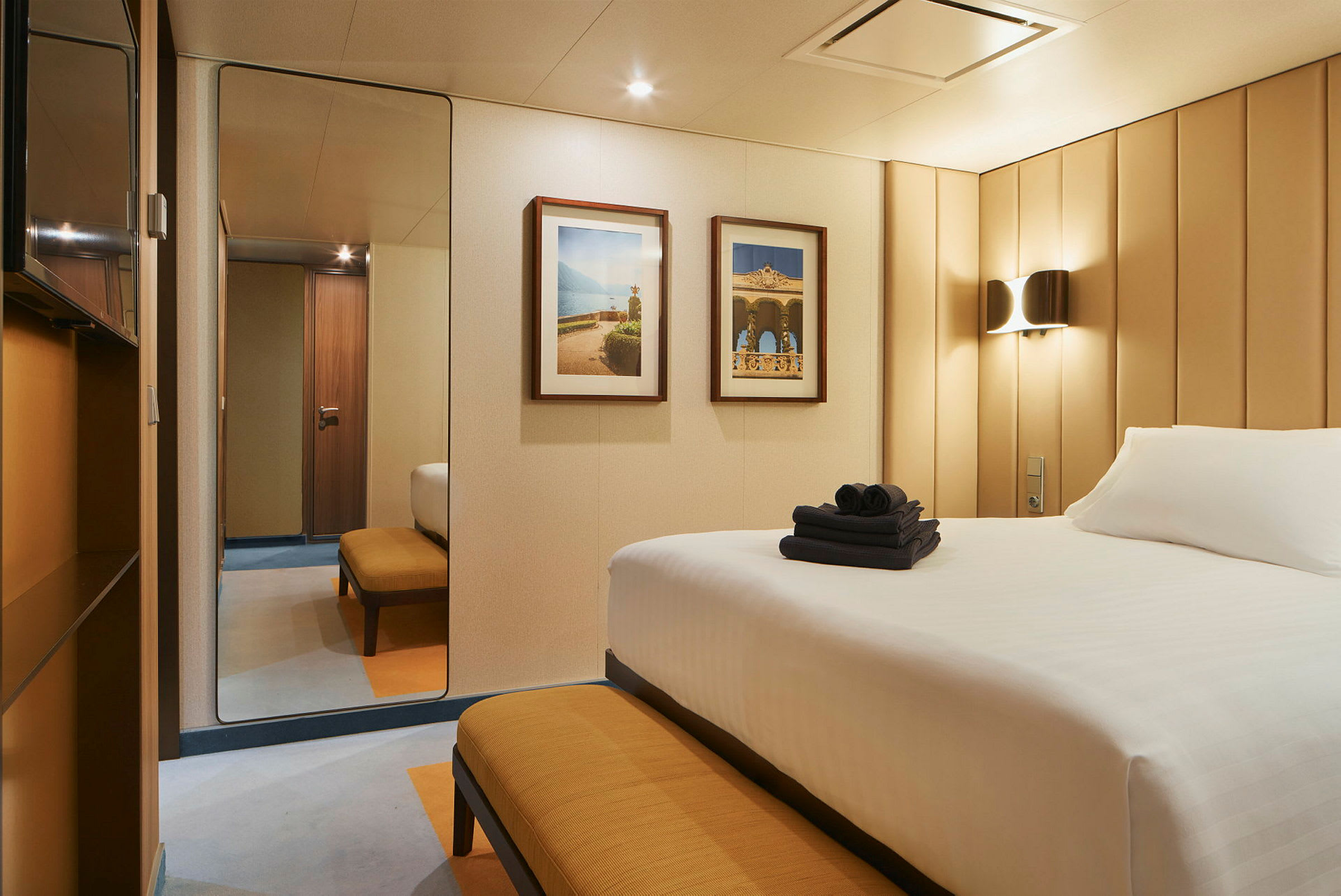 Ett hotellrum med en säng, en bänk och två tavlor på väggen. (AI-genererad text)