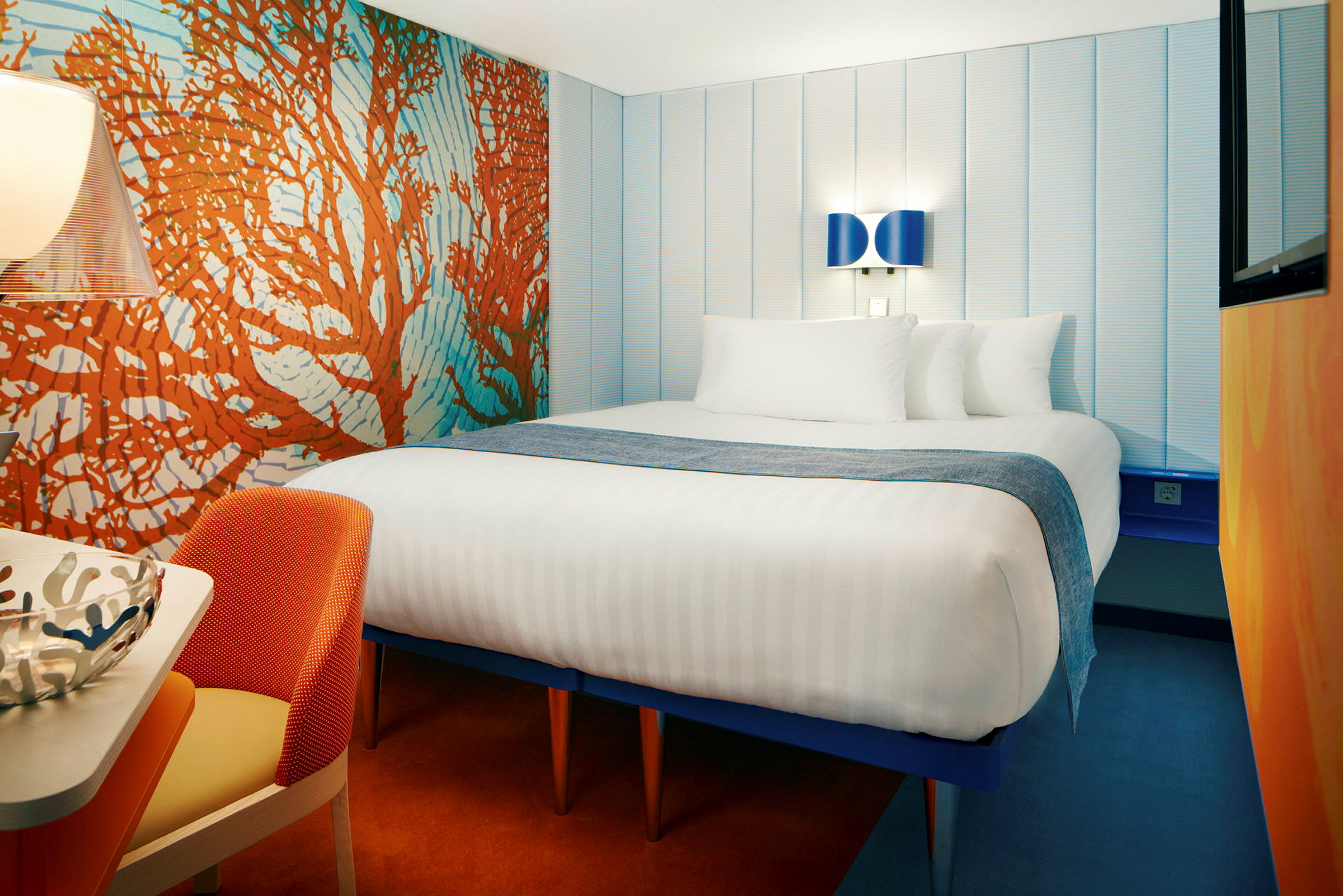 Hotellrum med en stor säng, färgglad inredning och modern belysning. (AI-genererad text)