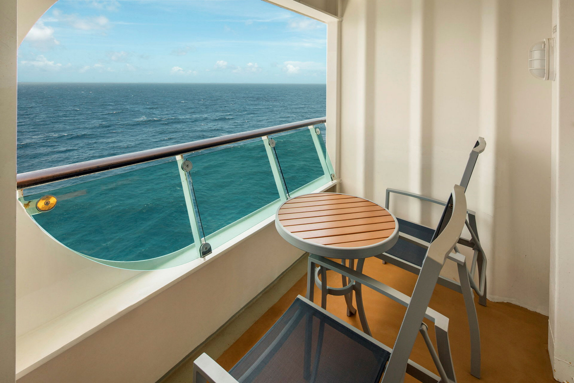 Utsikt från en balkong med ett bord och två stolar, över havet. (AI-genererad text)