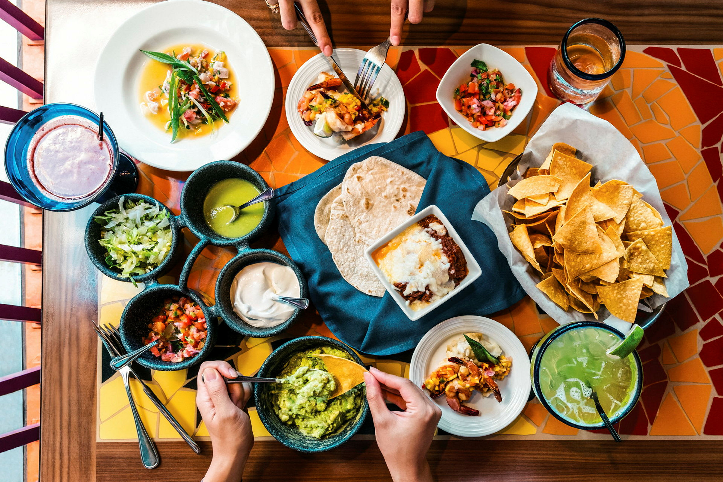 En bord dukat med mexikansk mat, inklusive tacos, guacamole, chips och salsor. (AI-genererad text)