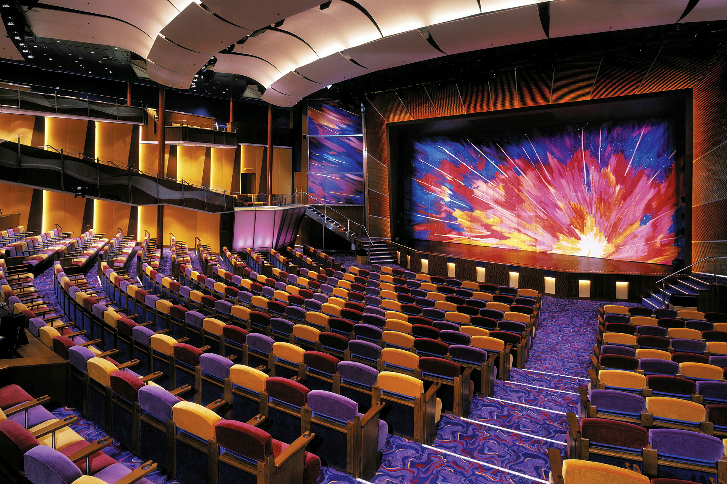 Bild på ett auditorium med färgglada sitsar och en scen med en färgglad ridå. (AI-genererad text)