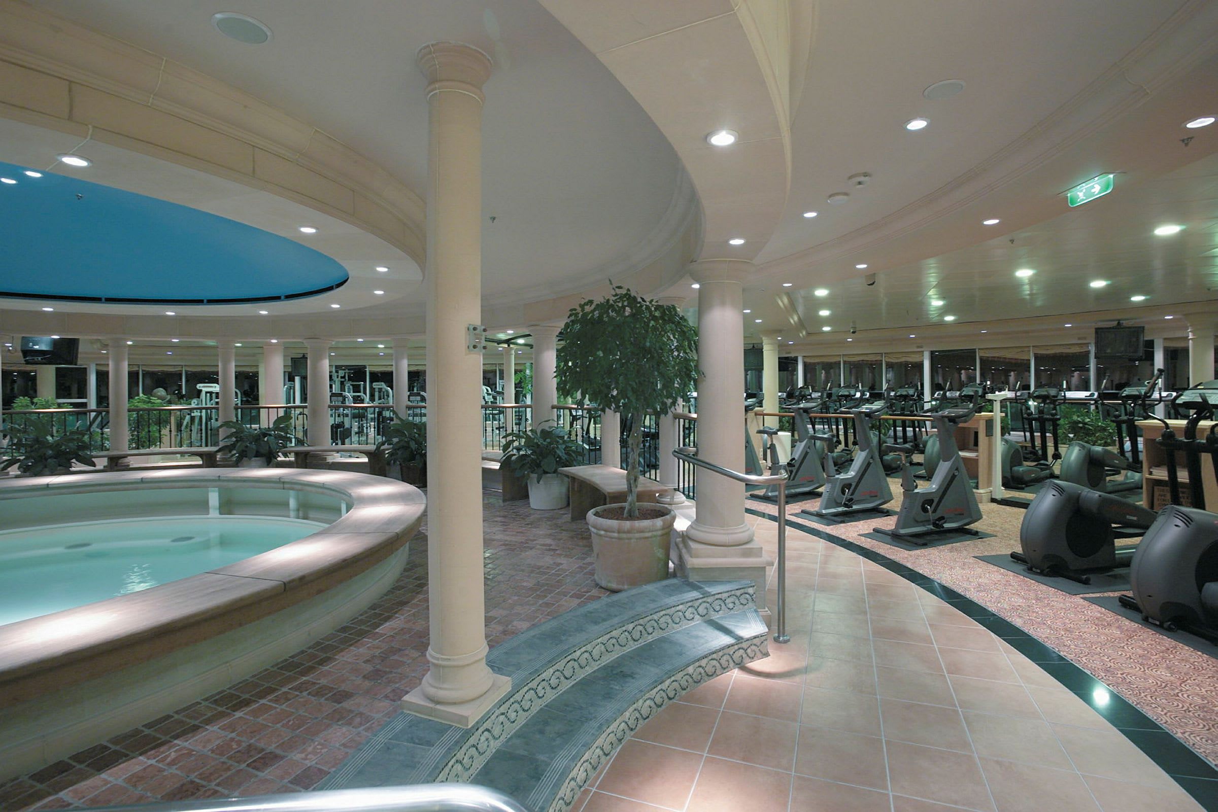 Interiörbild av ett gym med träningsutrustning och en mindre pool. (AI-genererad text)