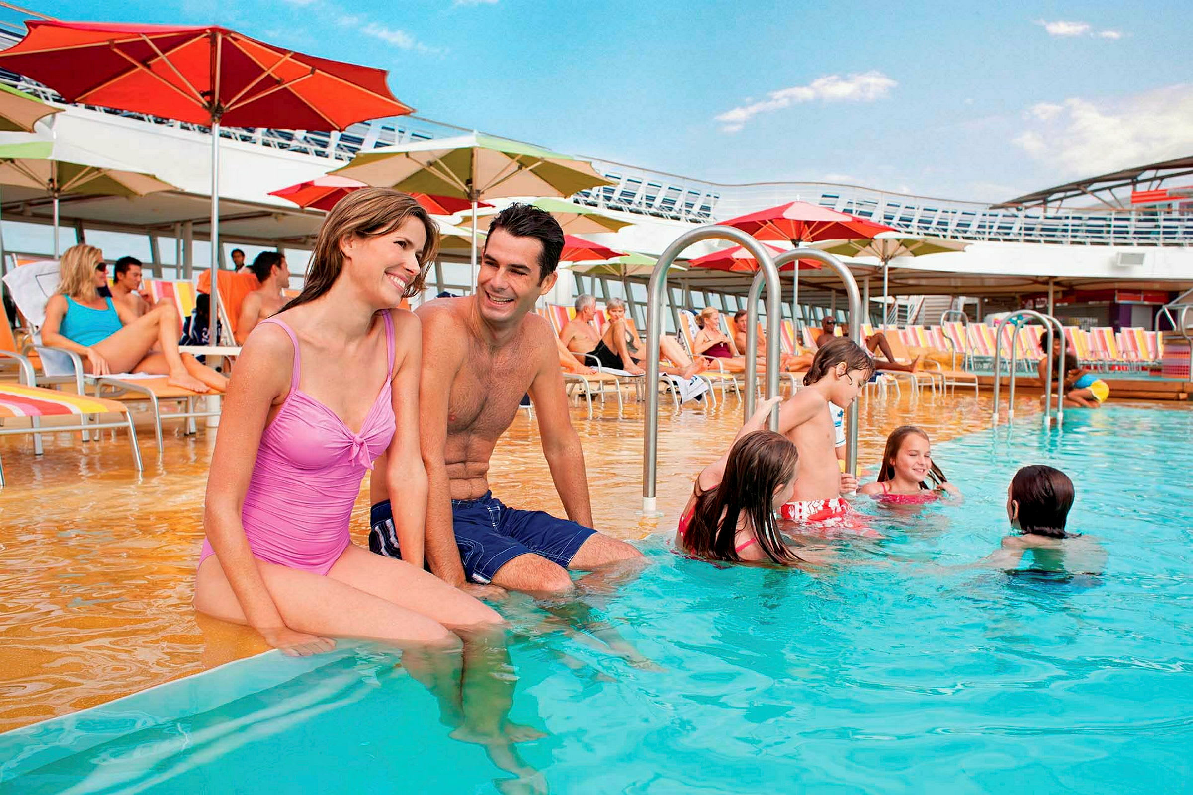 Personer står och sitter vid en pool på ett fartyg med solstolar och parasoller i bakgrunden. (AI-genererad text)