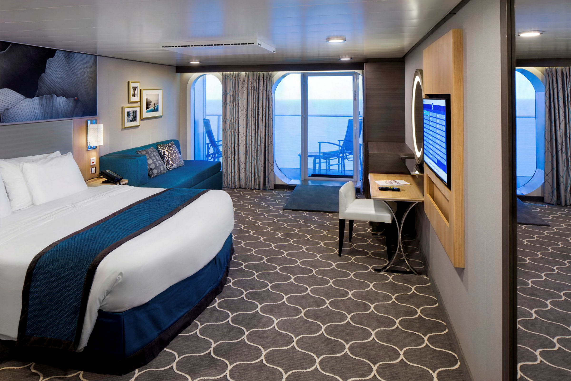 Ett hotellrum med säng, soffa, skrivbord och balkong med utsikt över havet. (AI-genererad text)