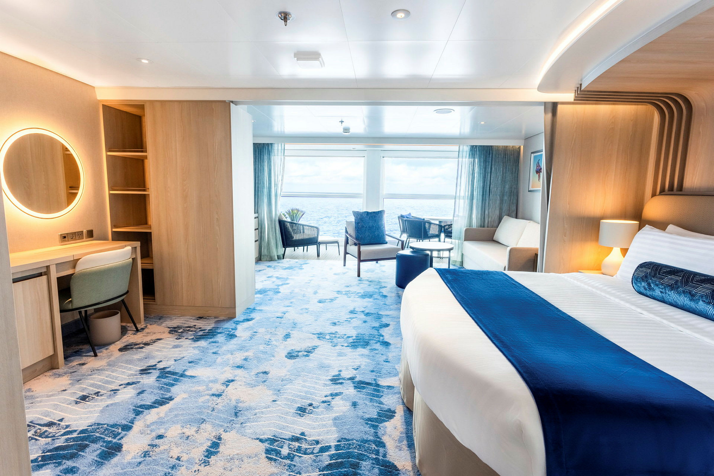 Hotellrum med utsikt över havet, möblerat med säng, soffa och skrivbord. (AI-genererad text)