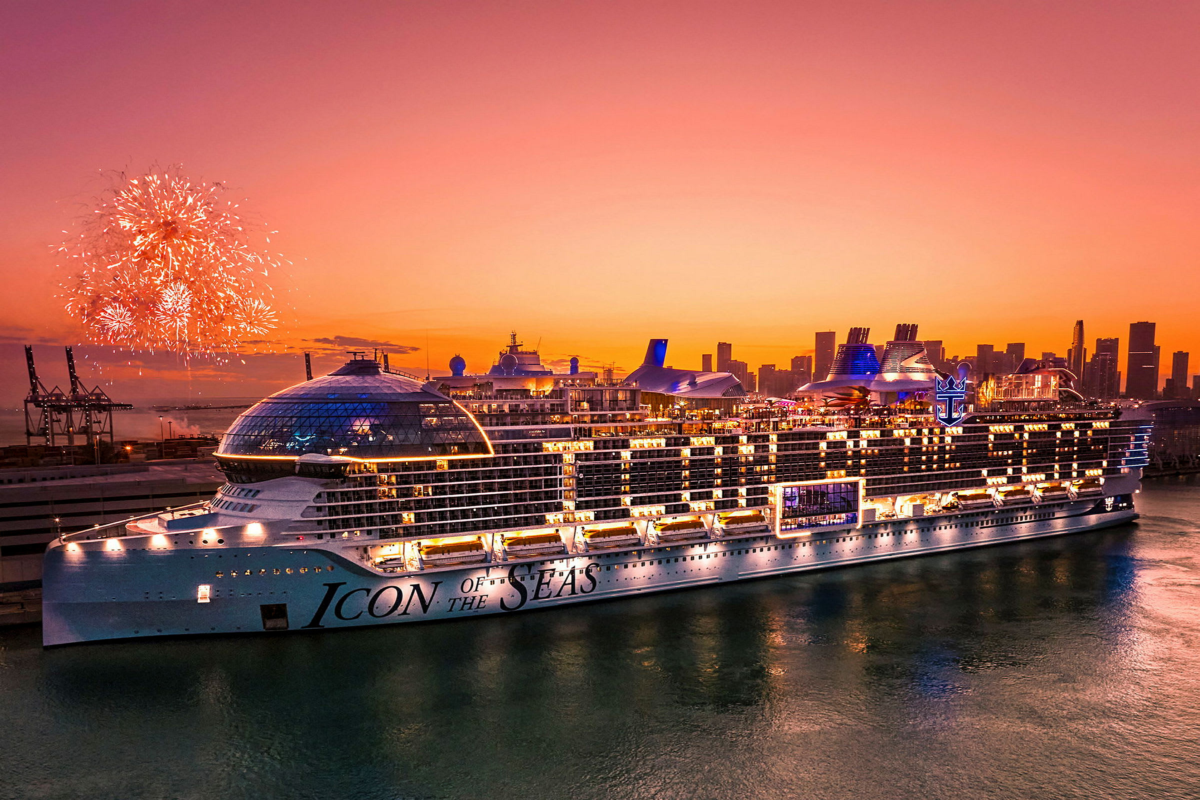 Ett stort kryssningsfartyg med namnet 'Icon of the Seas' synlig mot en solnedgång, medan fyrverkerier lyser upp natthimlen. (AI-genererad text)