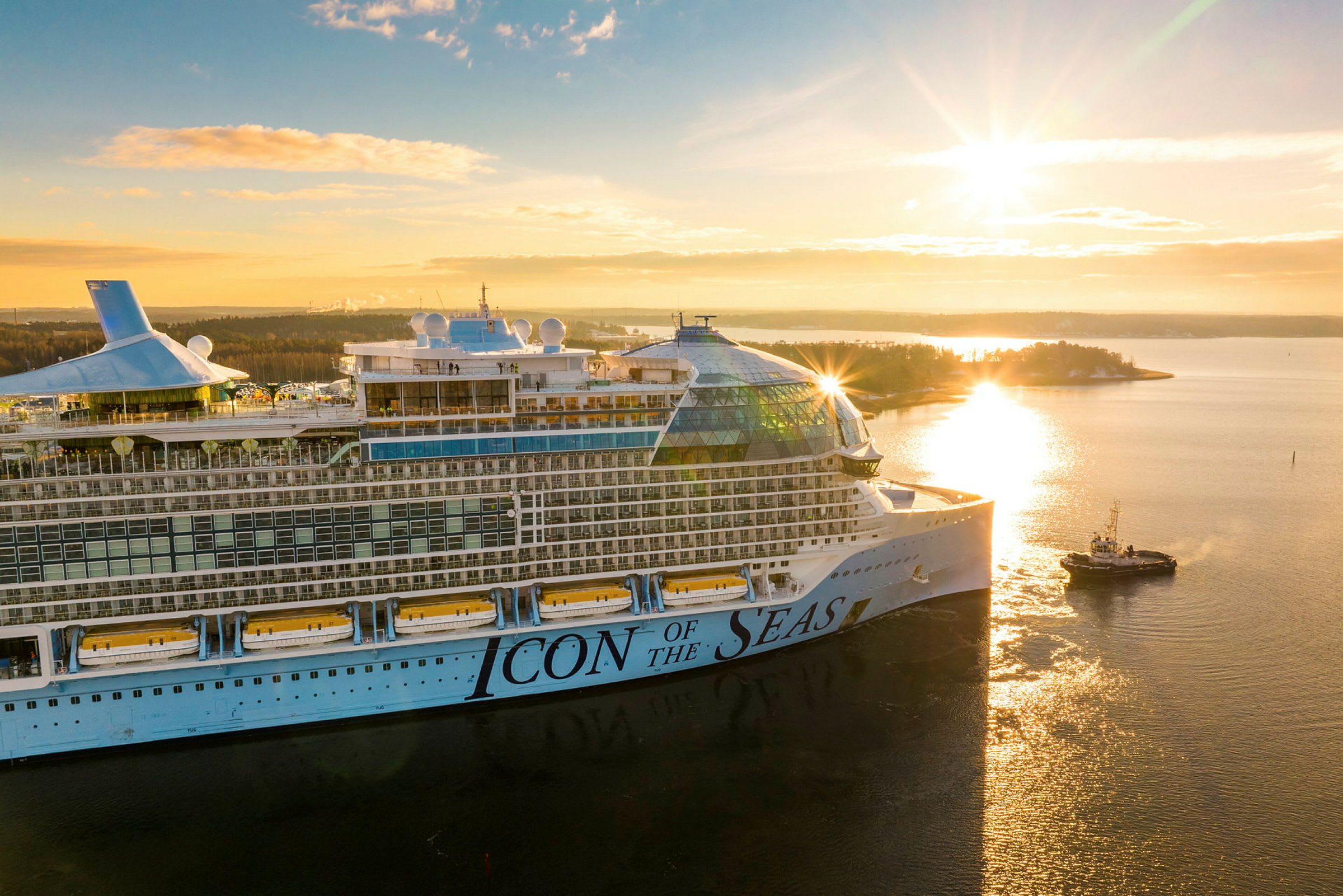 Ett kryssningsfartyg med texten 'Icon of the Seas' på sidan syns i soluppgång över en sjö. (AI-genererad text)