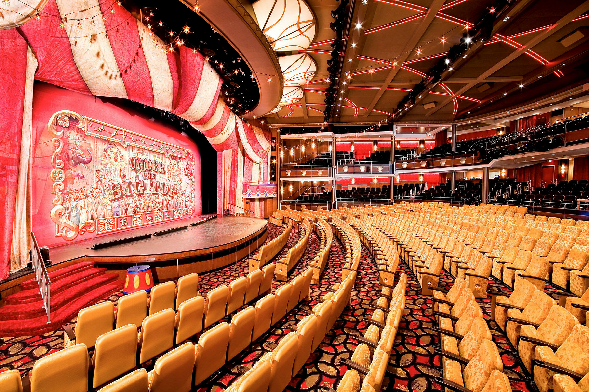 En teatersal med röda och gula dekorationer runt scenen och platser för publiken. (AI-genererad text)