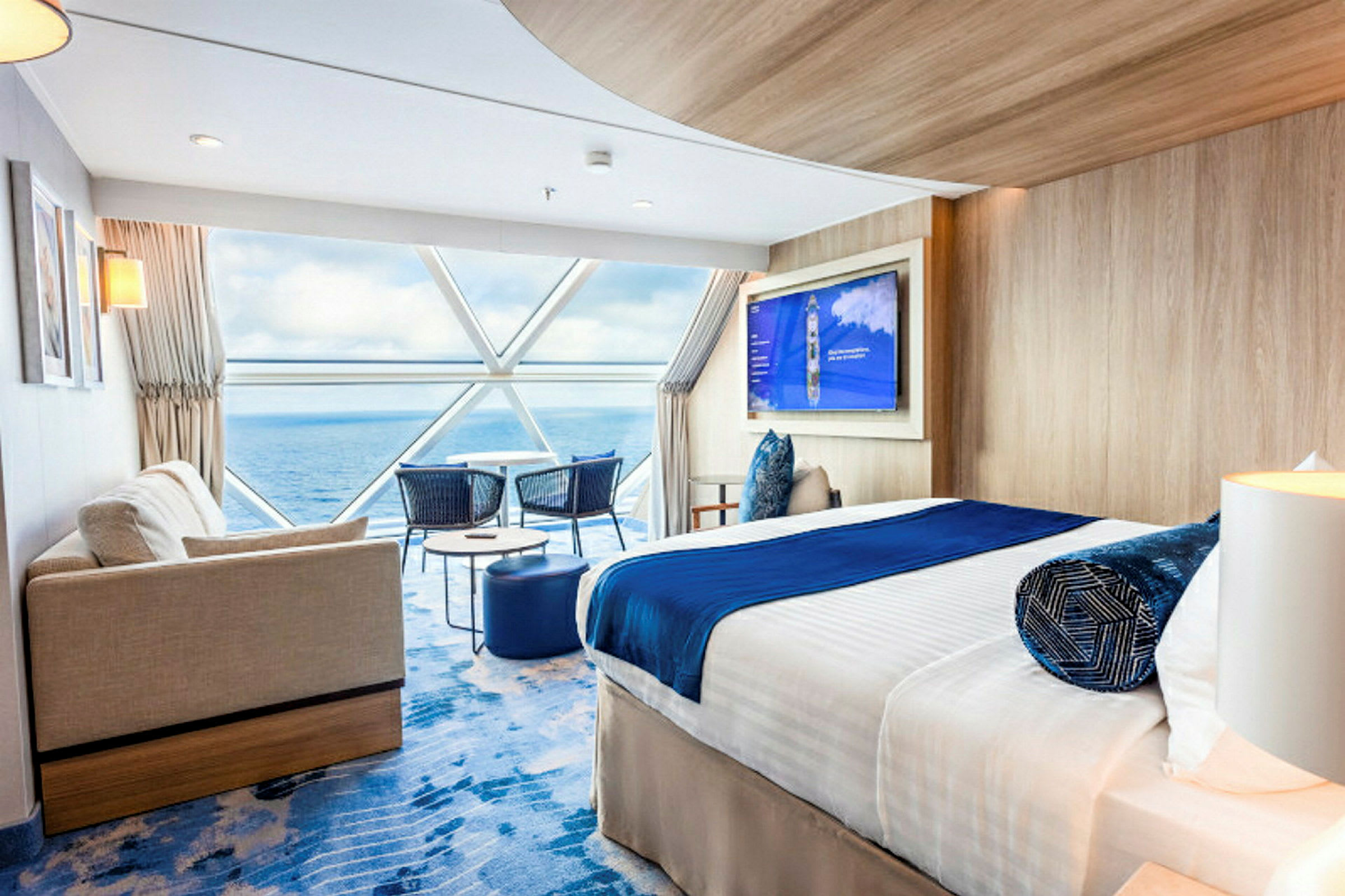 Modern hotellrum med säng, soffa och utsikt över havet genom stora fönster. (AI-genererad text)