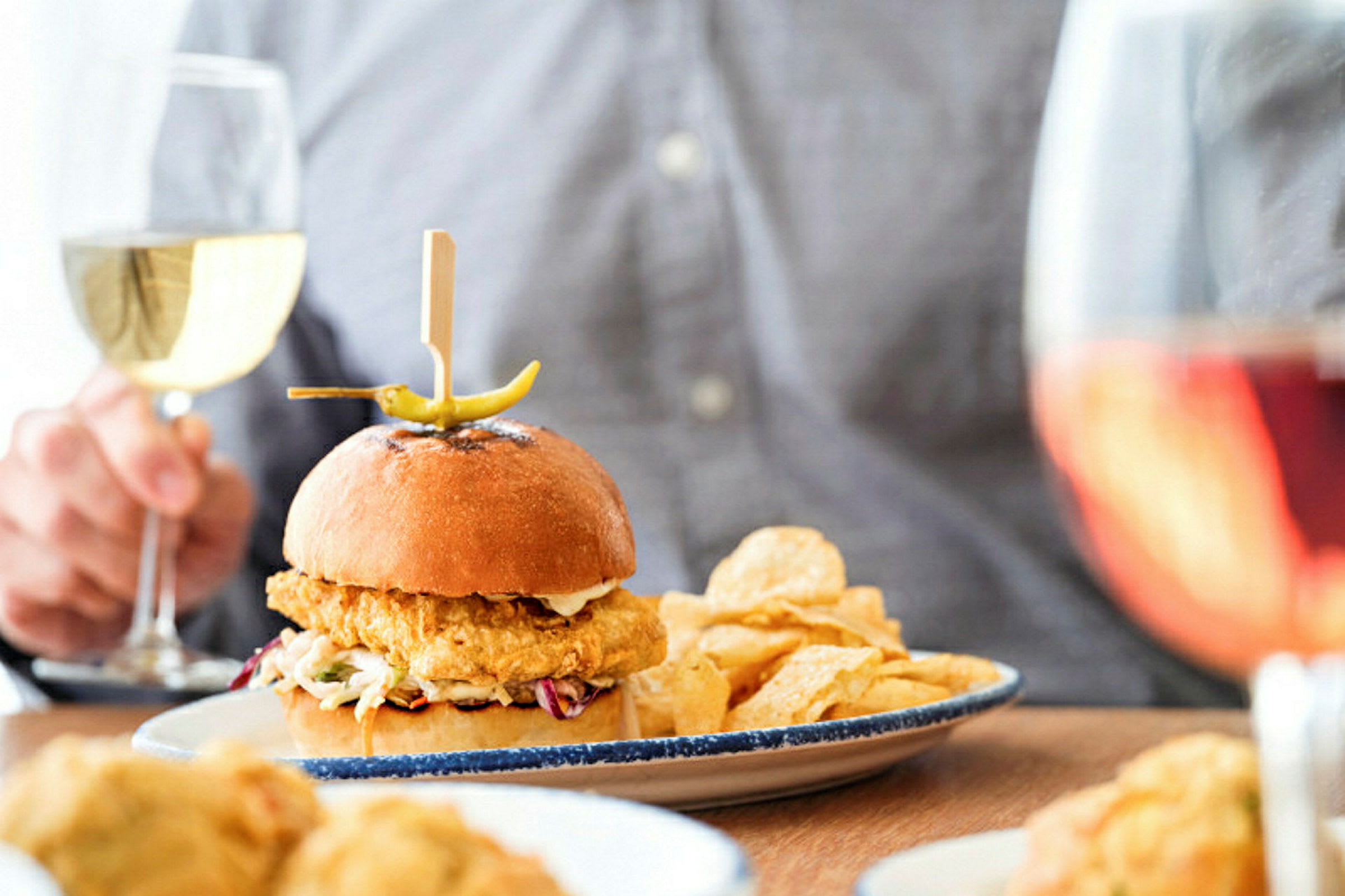 En tallrik med en hamburgare, chips och ett glas vin syns på bilden. (AI-genererad text)