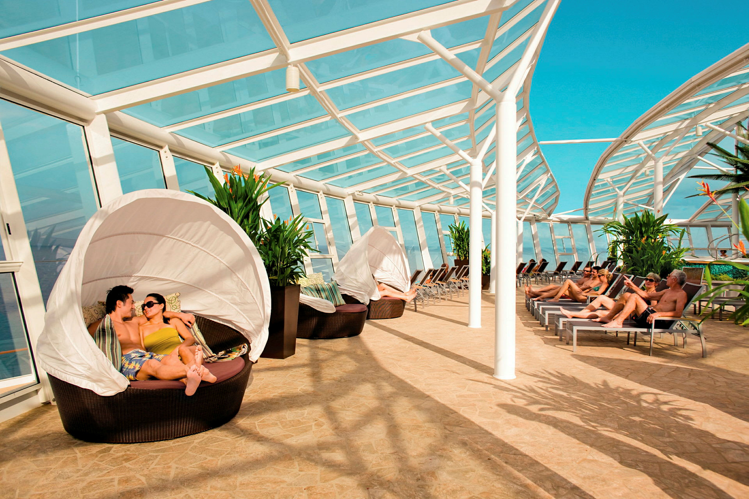 Solarium med tak från glas, solstolar och sittgrupper bredvid gröna växter. (AI-genererad text)