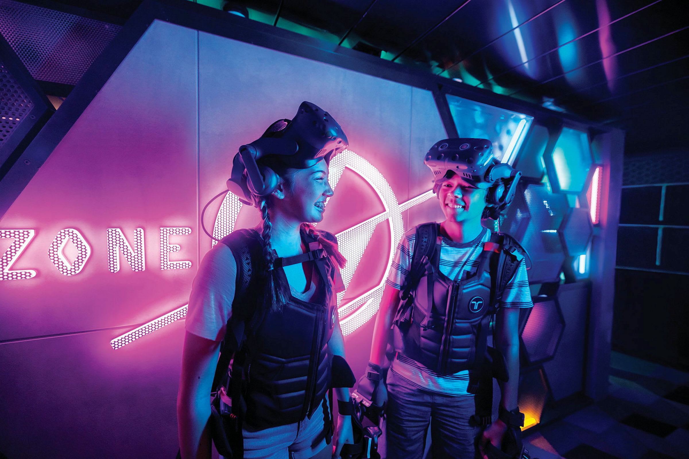 Två personer i en futuristisk miljö med VR-utrustning och neonljus. (AI-genererad text)