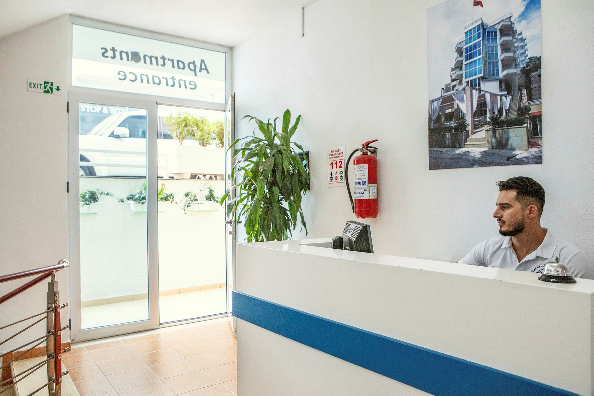 Reception i en lägenhetsbyggnad med en växt och en brandsläckare på väggen. (AI-genererad text)