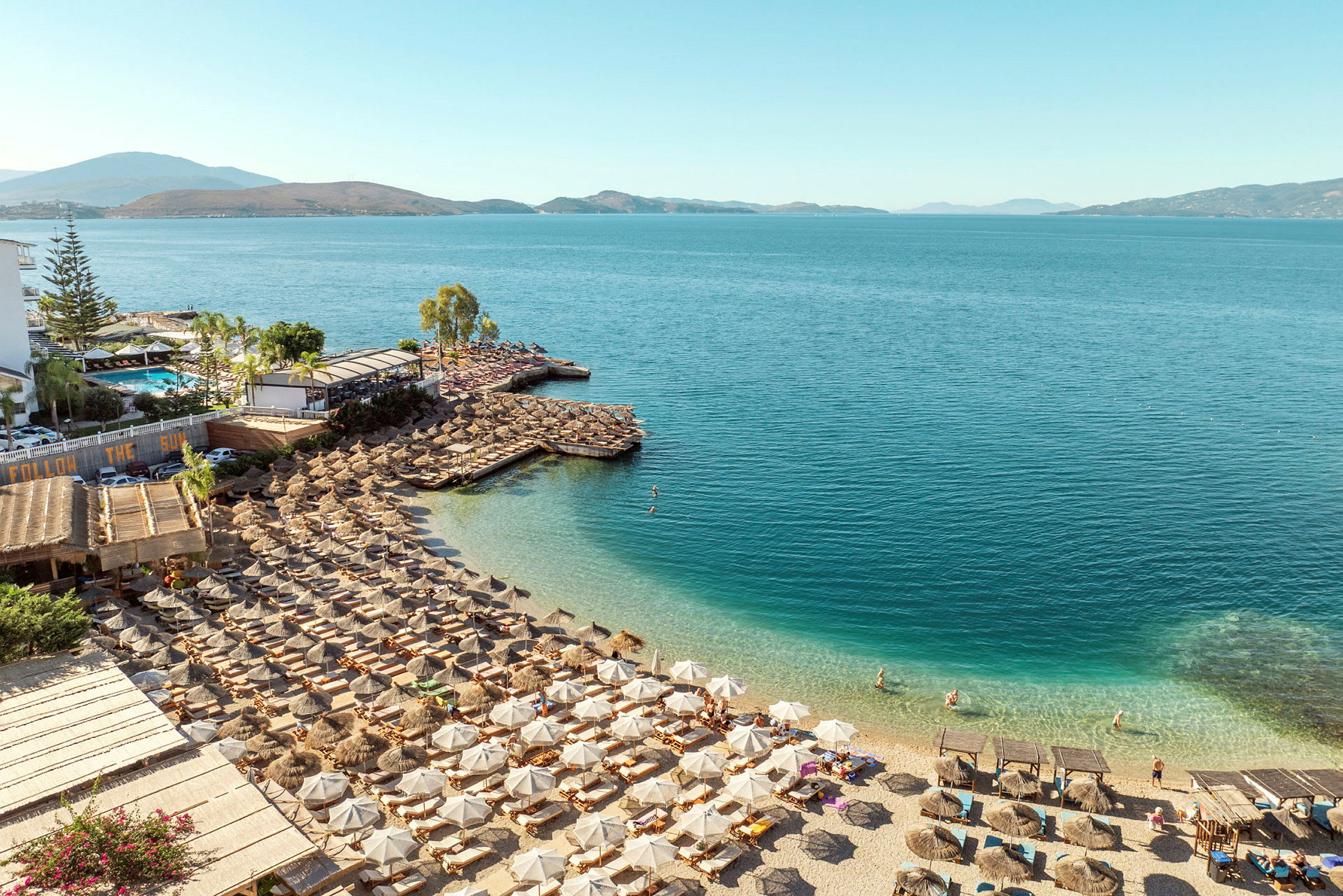 Strand med solstolar, parasoller och en klarblå havsutsikt. (AI-genererad text)