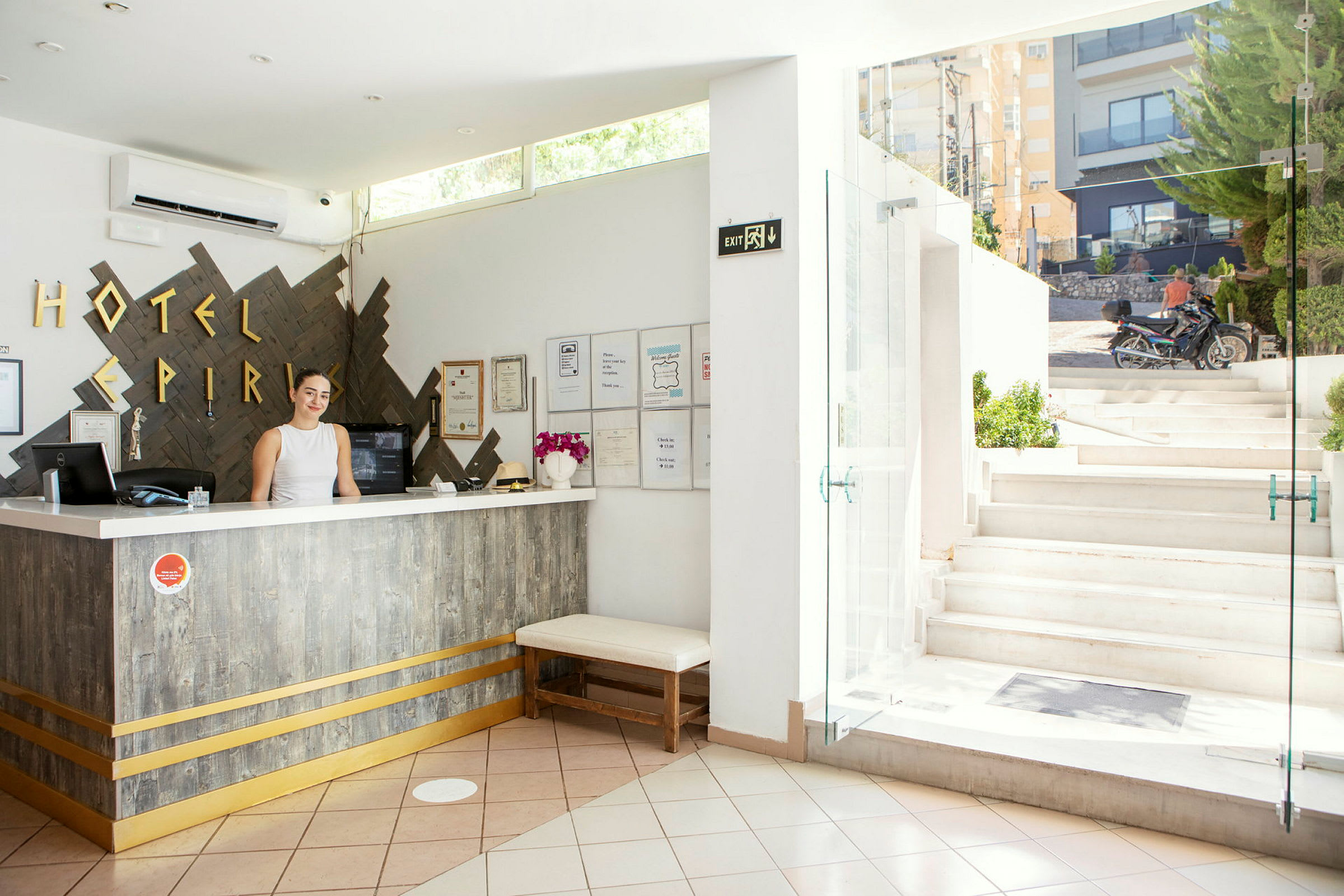Hotellobby med reception och öppning mot en utomhustrappa. (AI-genererad text)