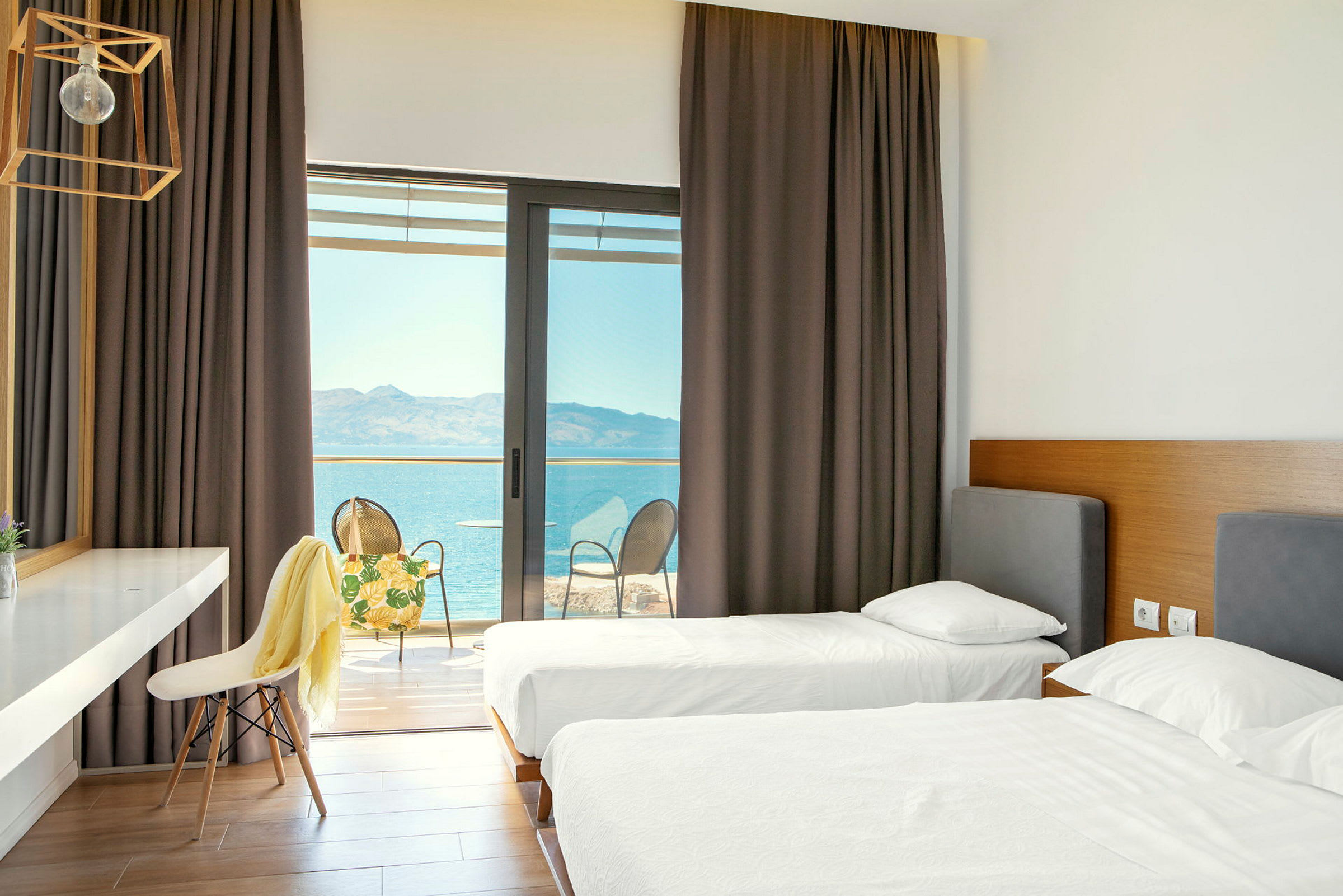 Hotellrum med två enkelsängar och utgång till en balkong med utsikt över havet. (AI-genererad text)