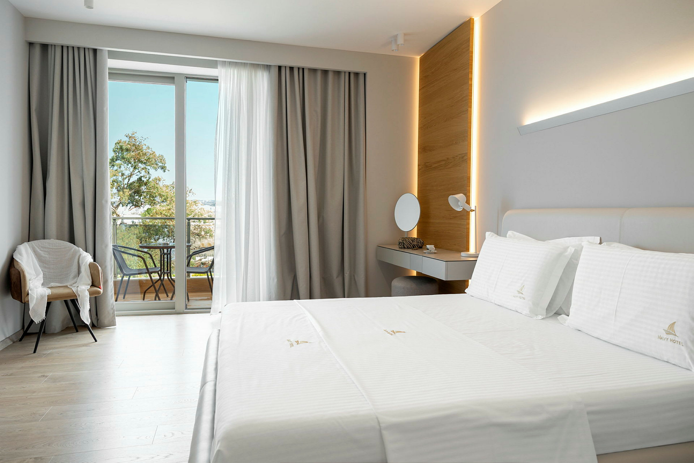 Ett modernt hotellrum med en stor säng, ett skrivbord, en stol och en balkong med möbler. (AI-genererad text)