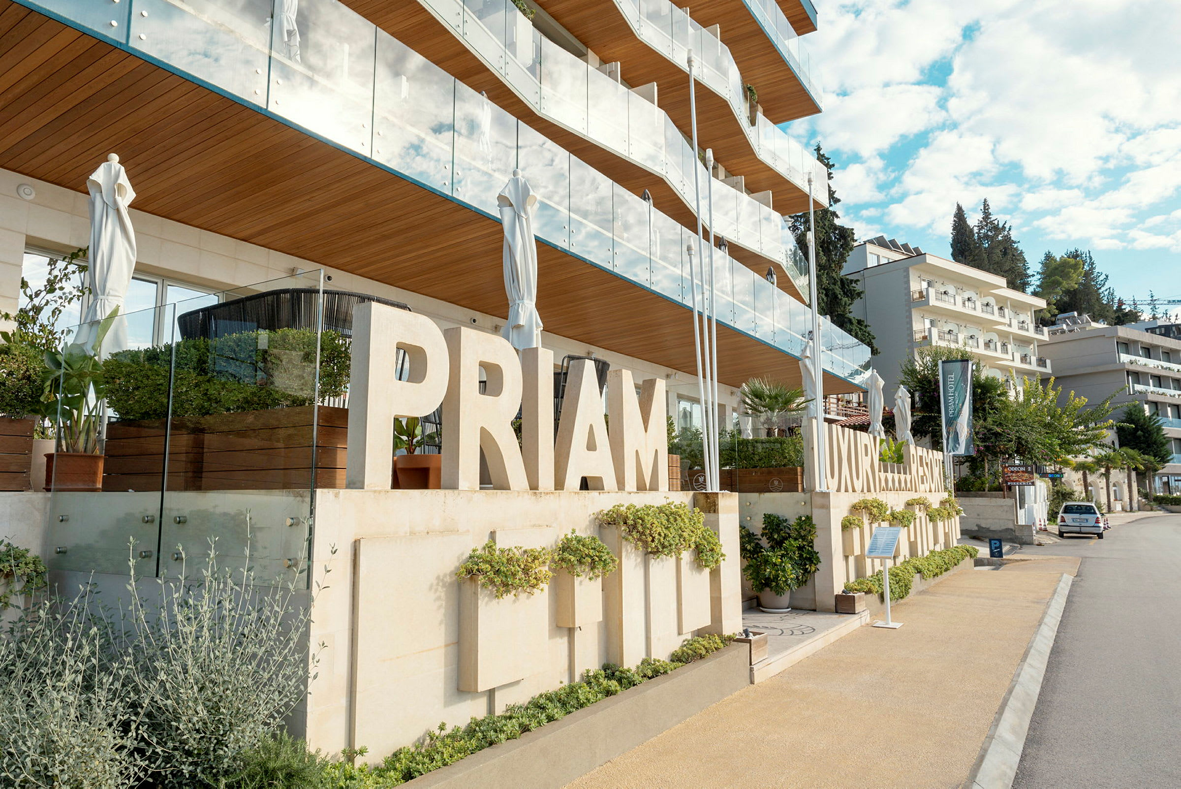 En modern byggnad med skyltar som säger 'PRIMAM LUXURY RESORT', omgiven av grönska och balkonger. (AI-genererad text)