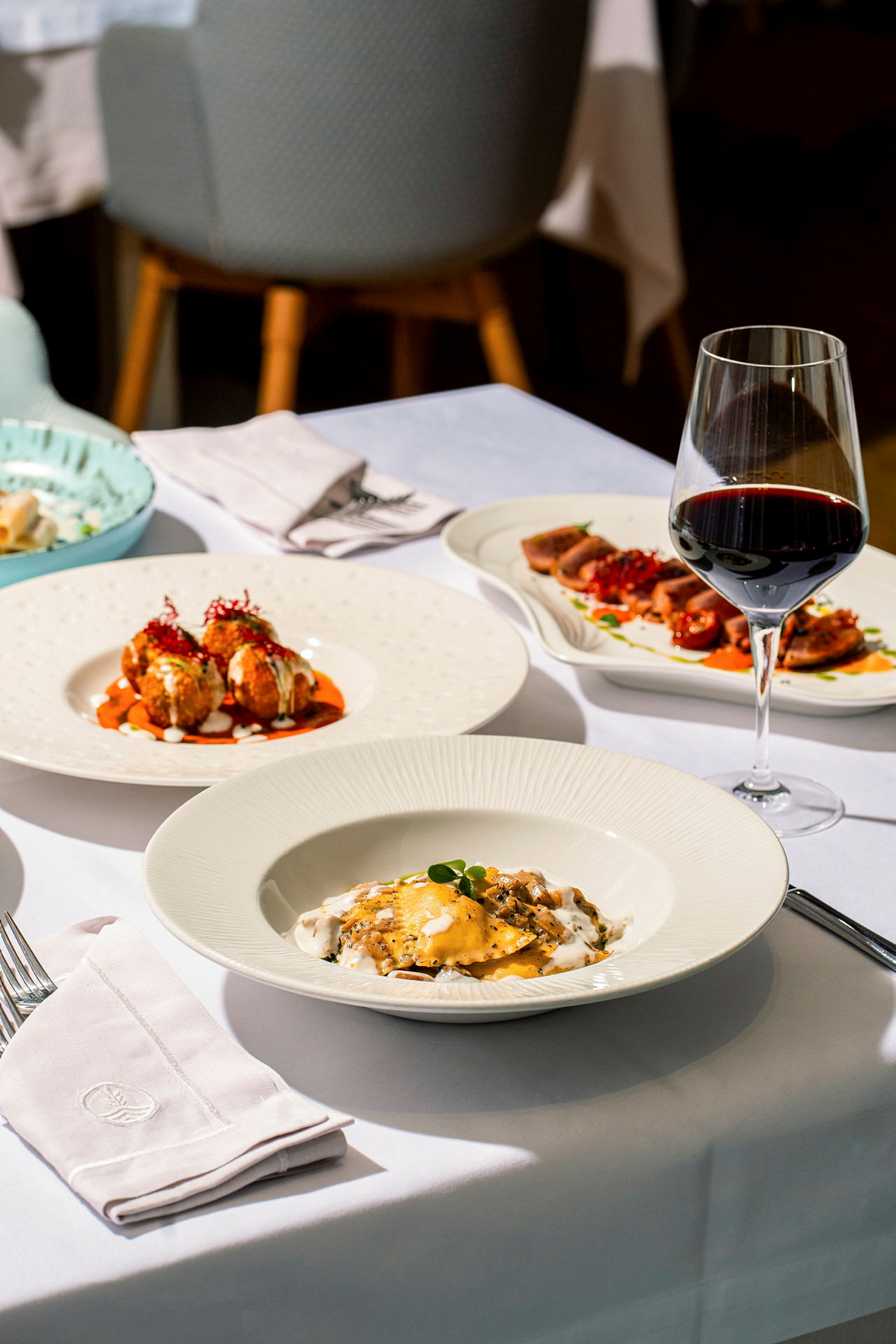 En dukad restaurangplats med olika maträtter och ett glas rött vin. (AI-genererad text)