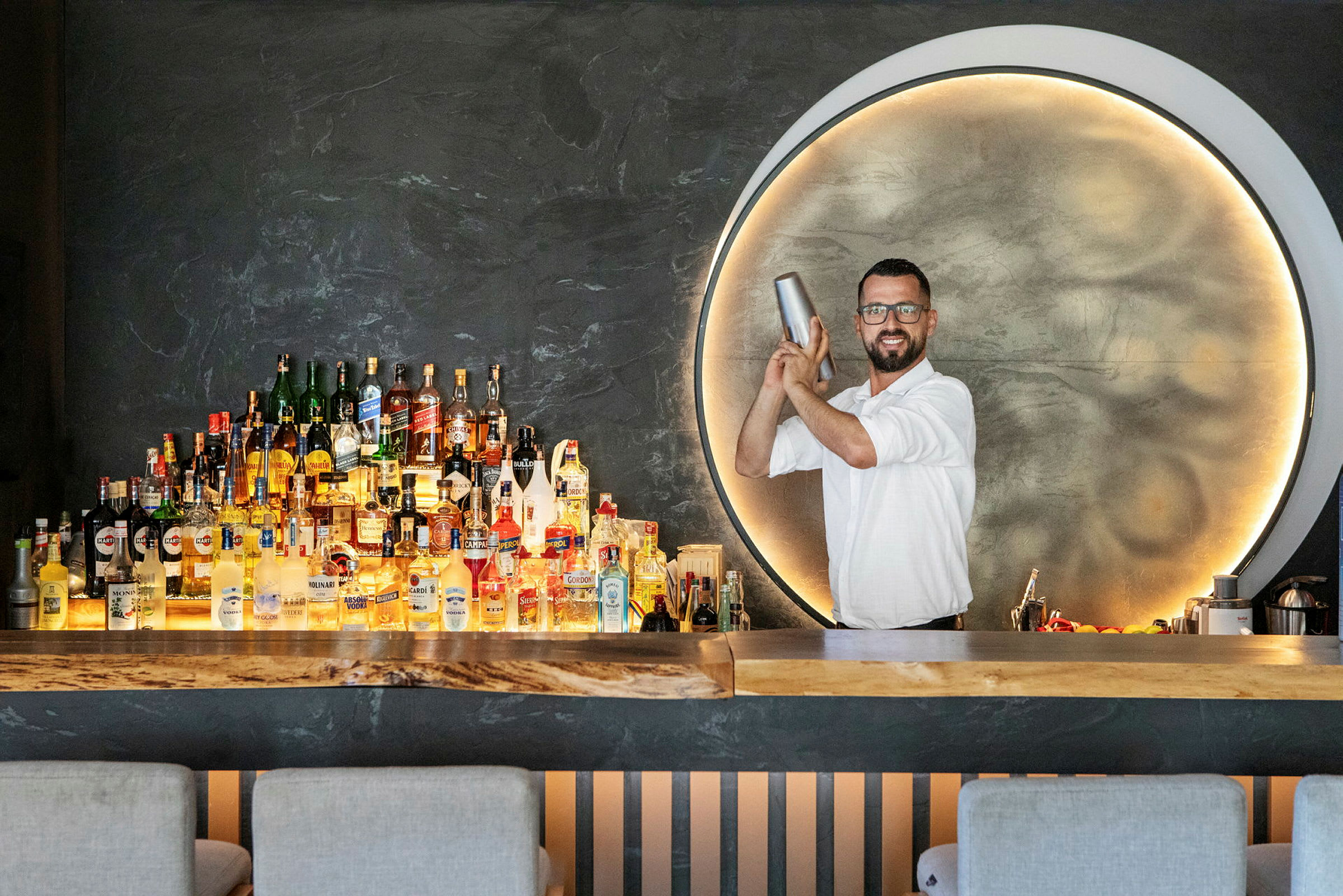 Bar med hylla fylld med olika spritflaskor och elegant bakgrundsbelysning. (AI-genererad text)