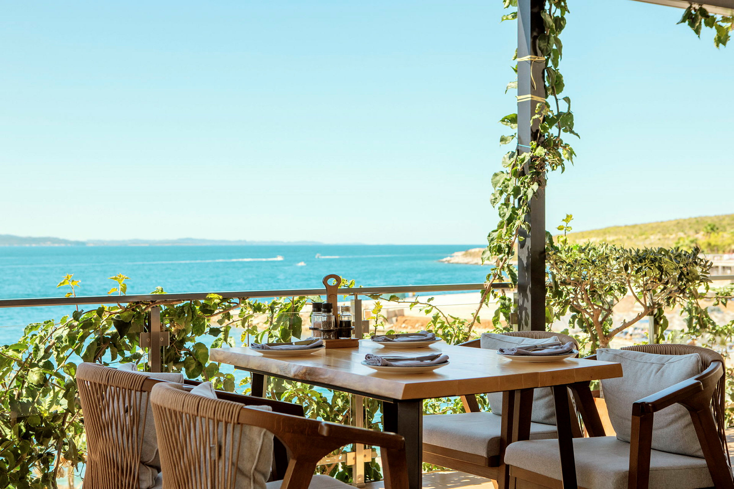 Uteservering med bord och stolar vid havet. (AI-genererad text)