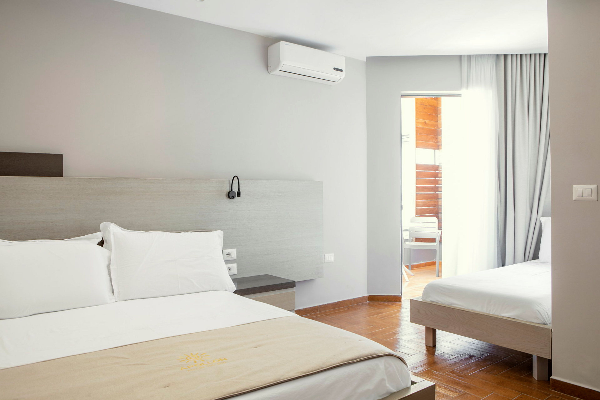 Hotellrum med två sängar och en dörr till balkongen. (AI-genererad text)