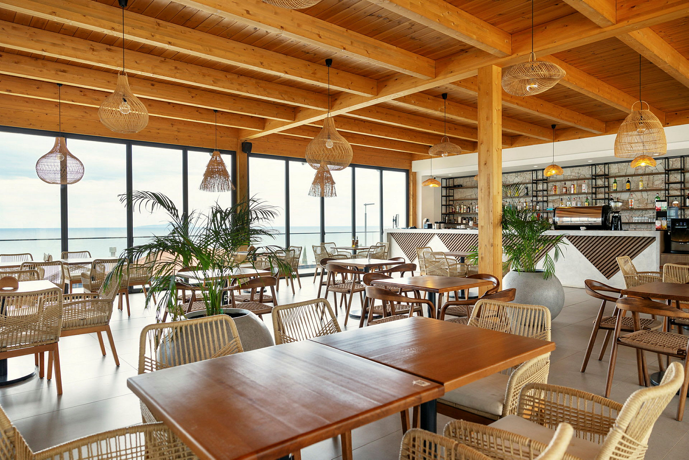 Restaurang med trämöbler, stora glasfönster och hängande lampor. (AI-genererad text)
