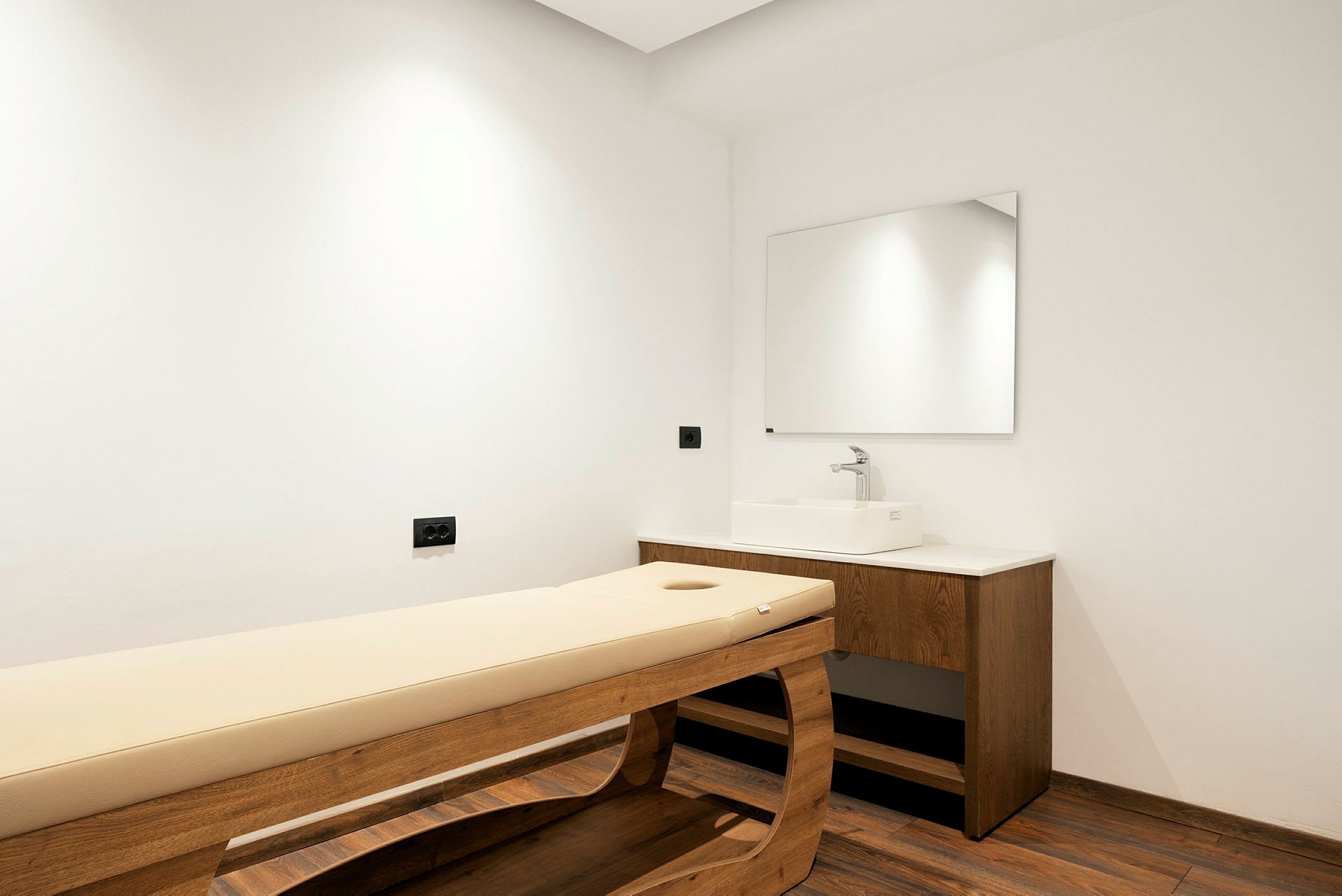 Massagebänk och diskho i ett behandlingsrum. (AI-genererad text)
