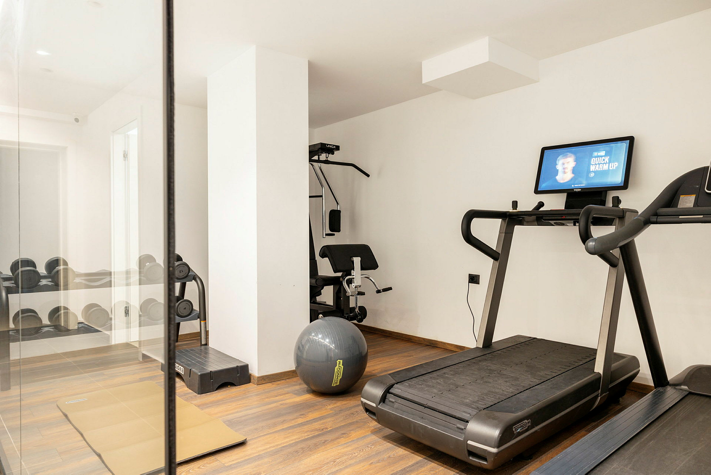 Ett gym med löpband, träningsbänk och hantlar. (AI-genererad text)