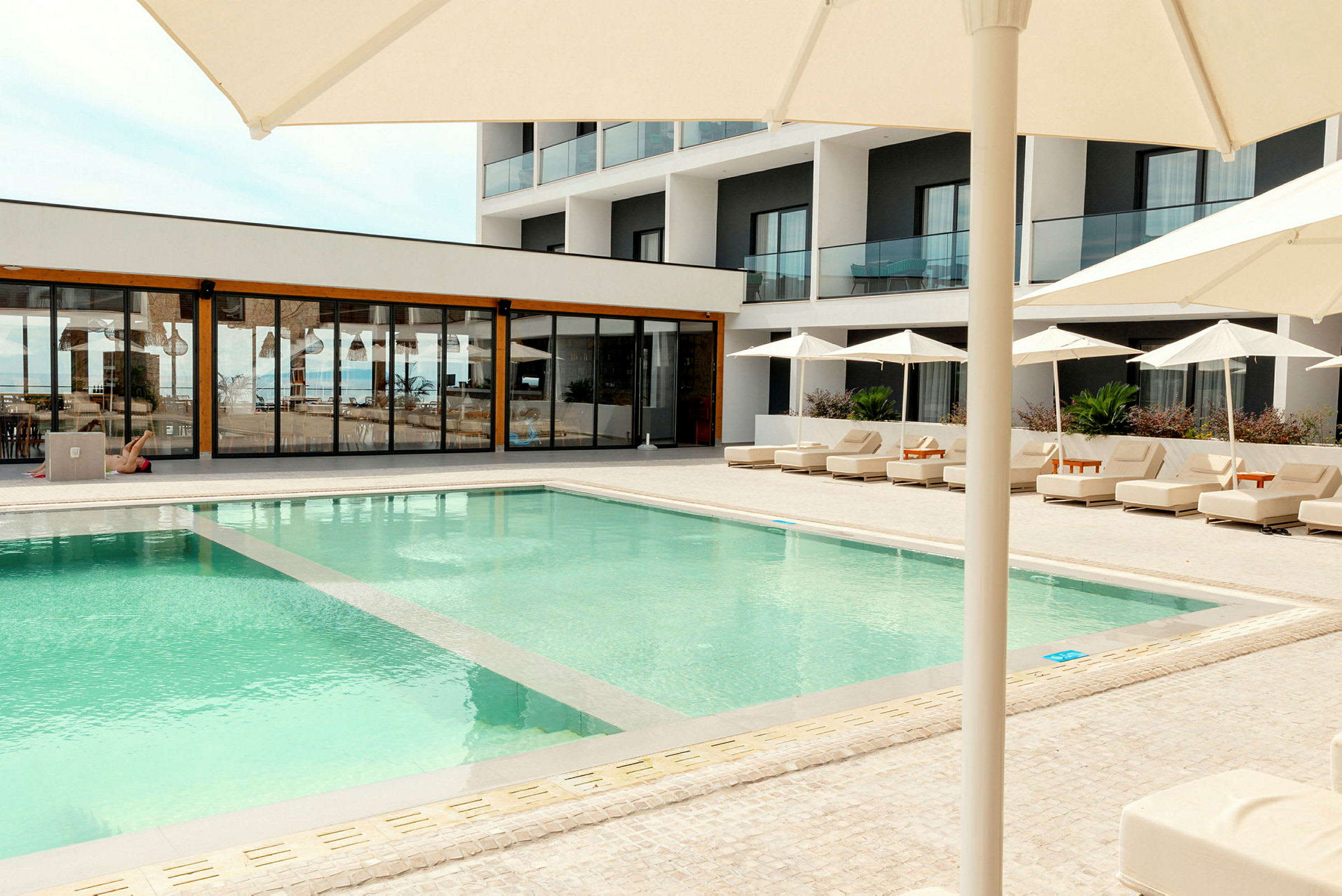 Utomhuspool vid ett modernt hotell med solsängar och parasoller. (AI-genererad text)