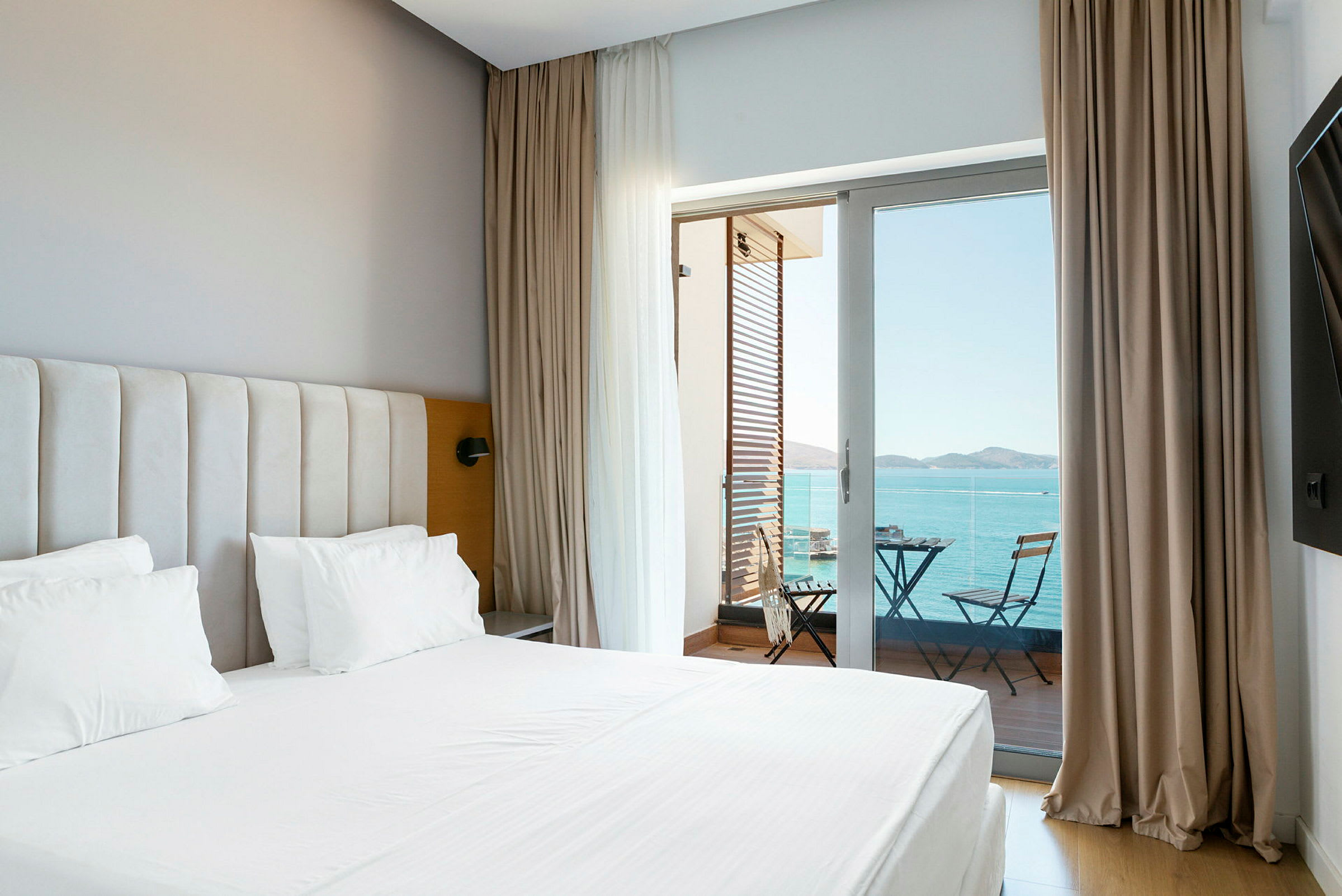 Bild på ett hotellrum med säng och en balkong med utsikt över havet. (AI-genererad text)