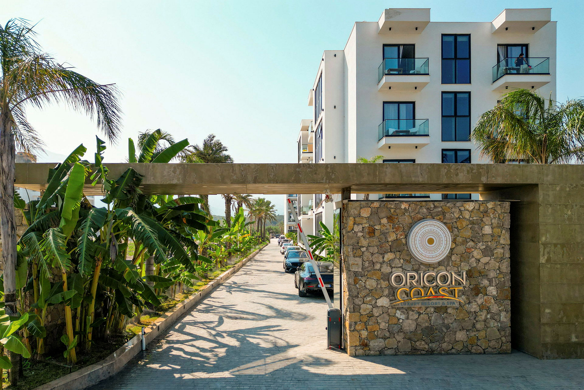 Entrén till Oricon Coast Luxury Resort & Spa med stenmur och logotyp. (AI-genererad text)