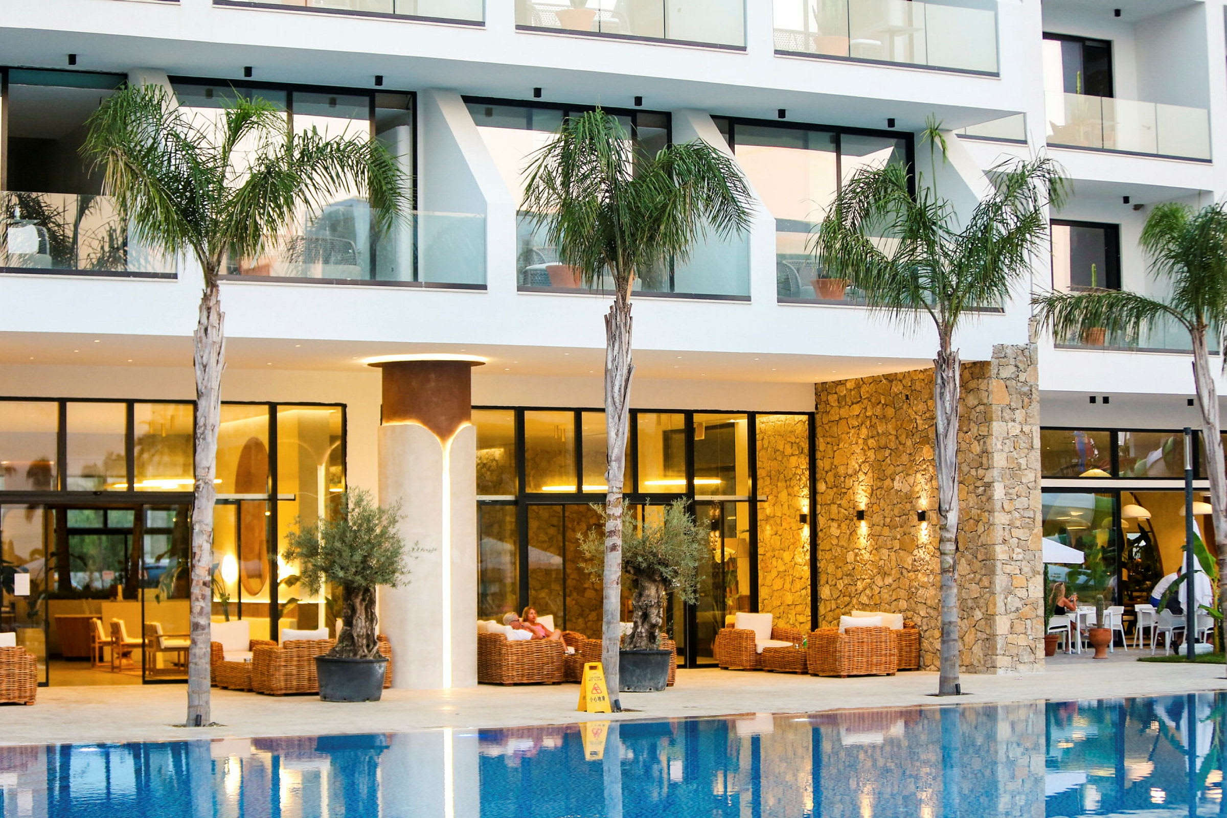 Ett hotell med moderna balkonger, palmer och pool samt utomhusmöbler. (AI-genererad text)