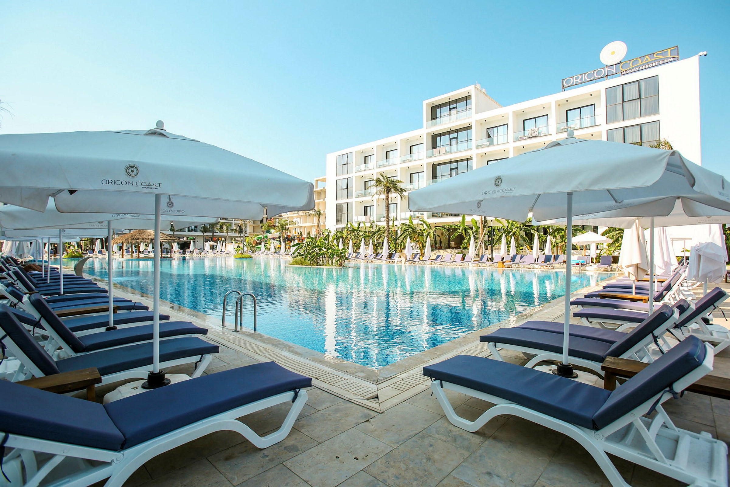 En poolkant med solstolar och parasoller vid ett modernt hotell. (AI-genererad text)